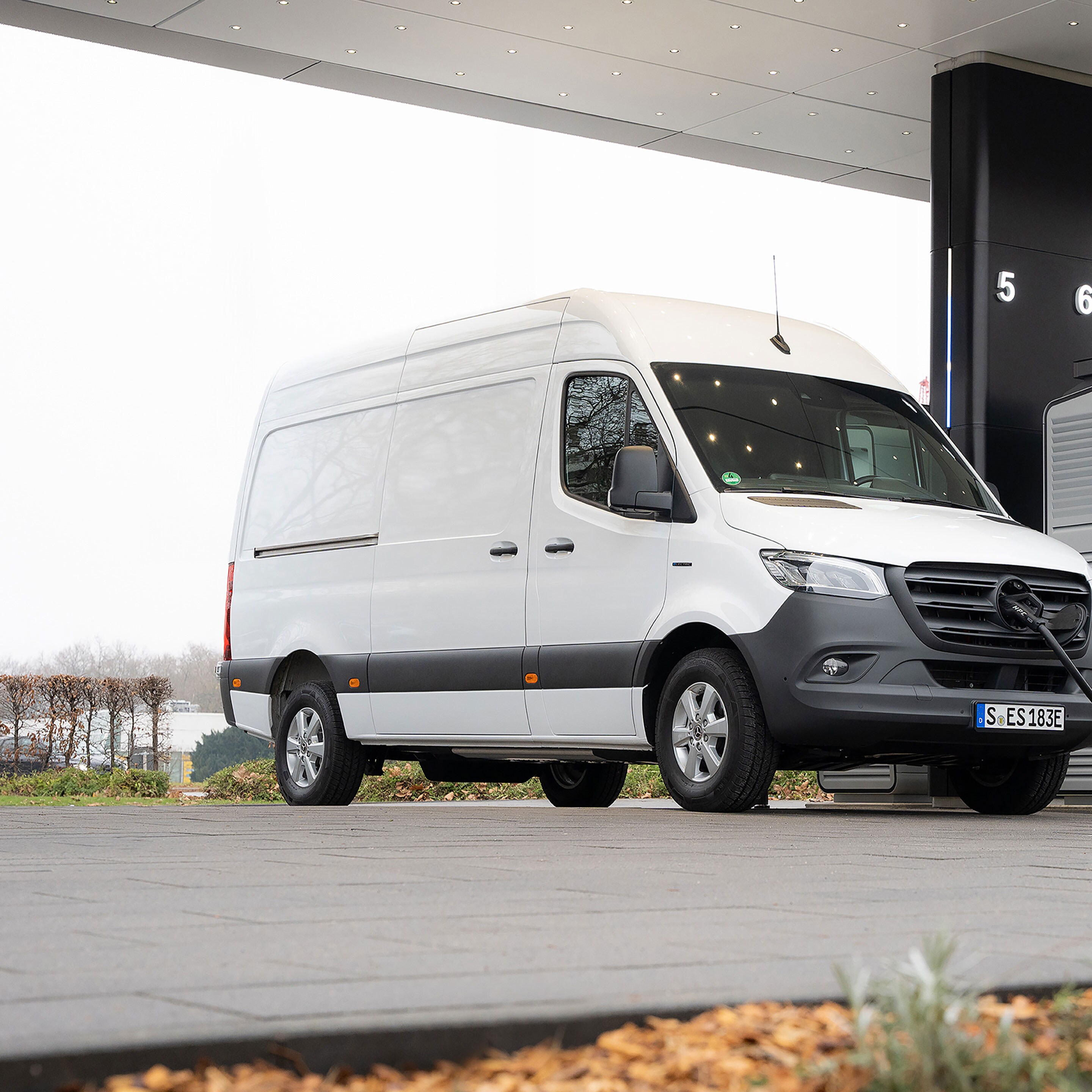 Samochód dostawczy Mercedes-Benz przed stacją ładowania podczas ładowania.