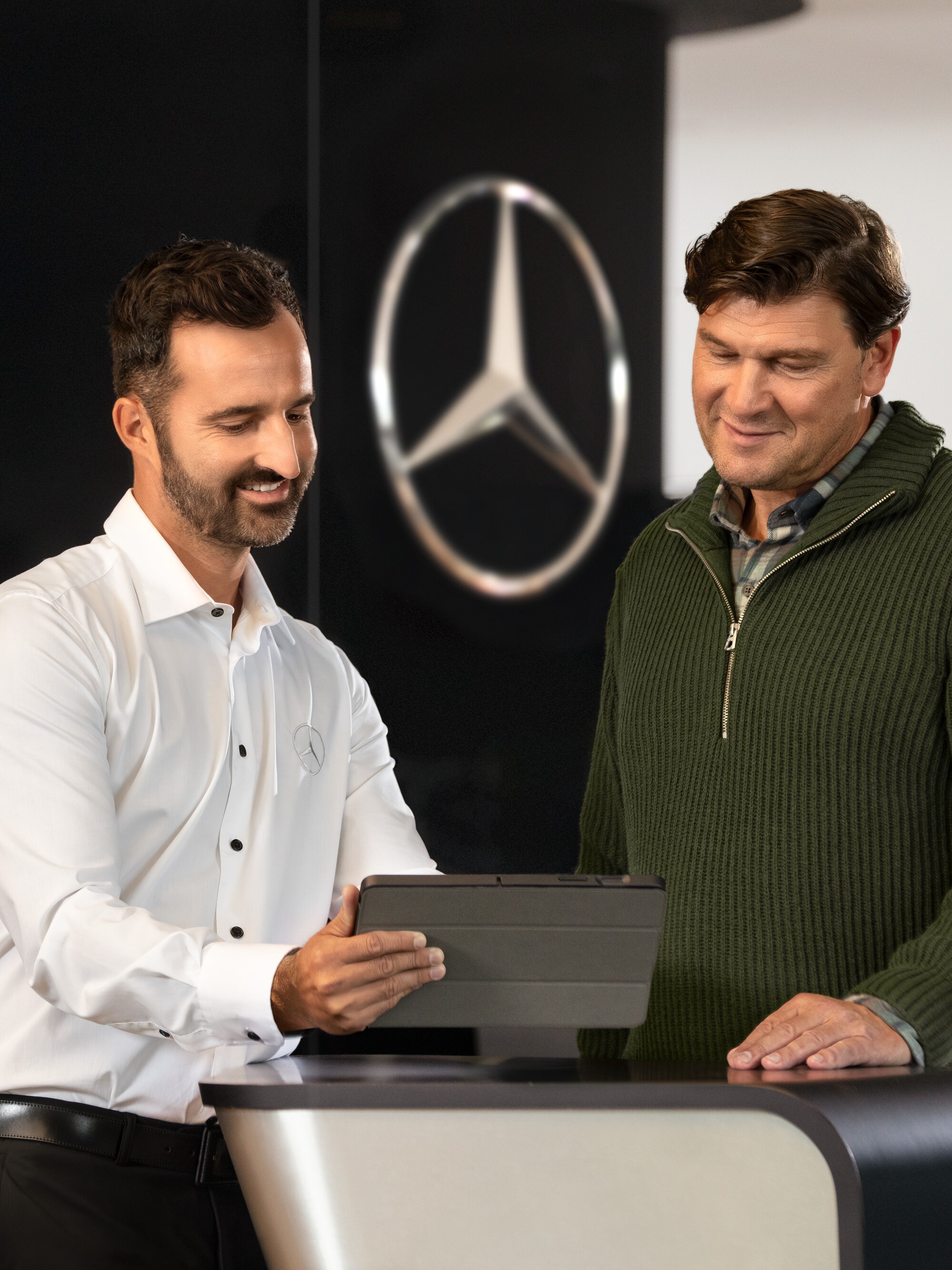Pracownik Mercedes-Benz rozmawia z klientem, patrząc na biurko.