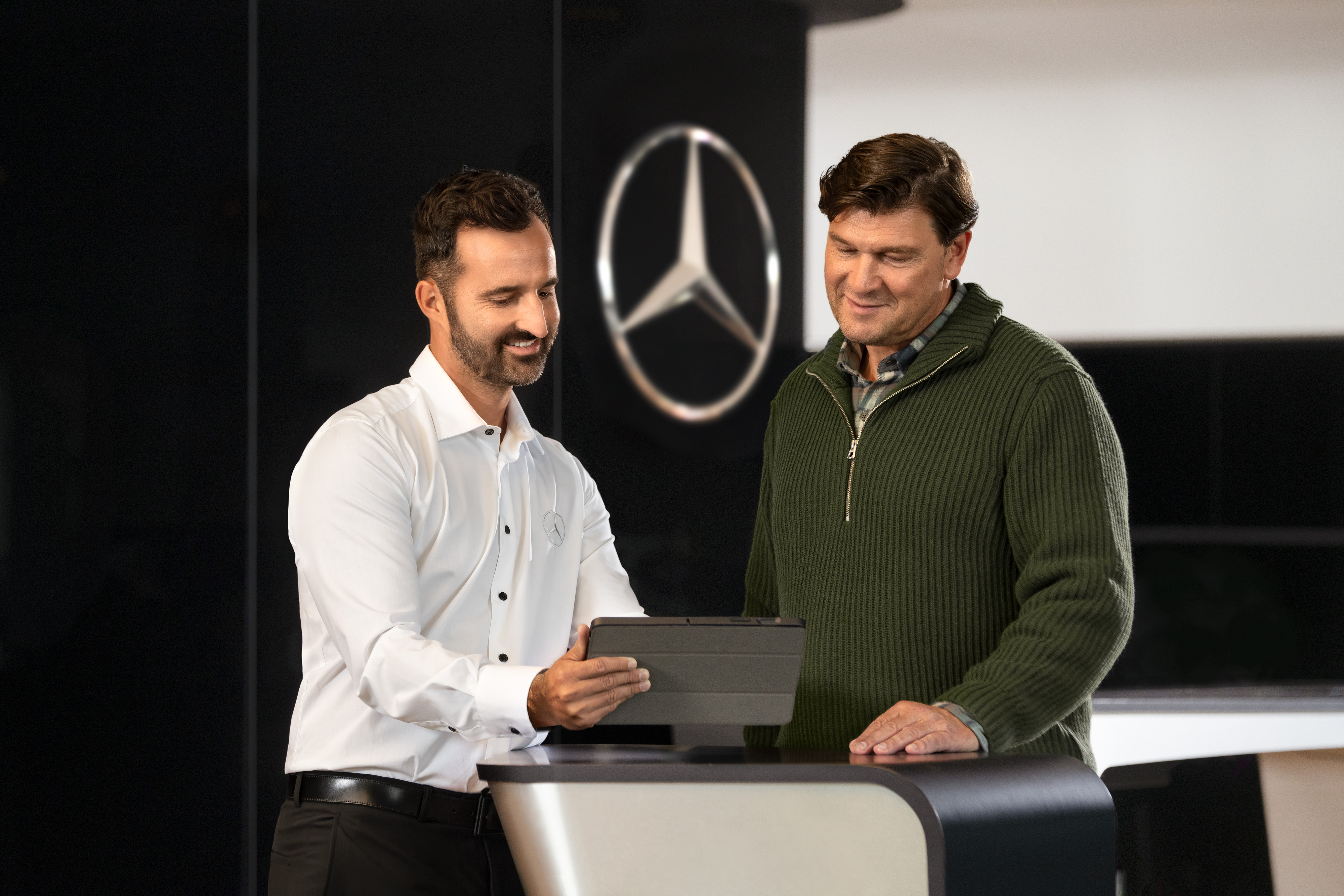 Wygoda | Samochody dostawcze Mercedes-Benz Pracownik Mercedes-Benz rozmawia z klientem, patrząc na biurko.