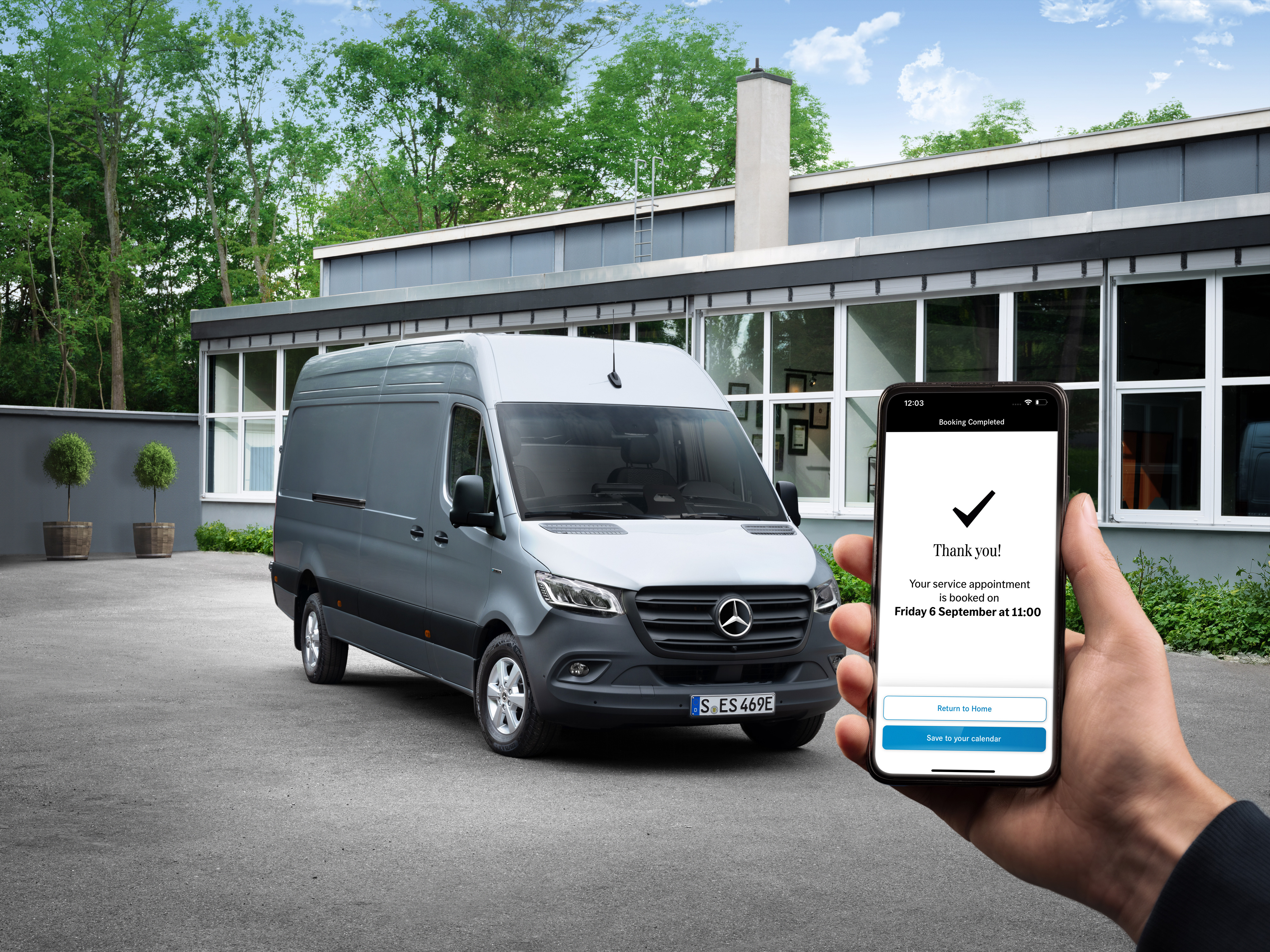 Partnerzy serwisowi | Samochody dostawcze Mercedes-Benz Szary samochód Mercedes-Benz Sprinter stojący przed biurem z osobą trzymającą smartfon na pierwszym planie.