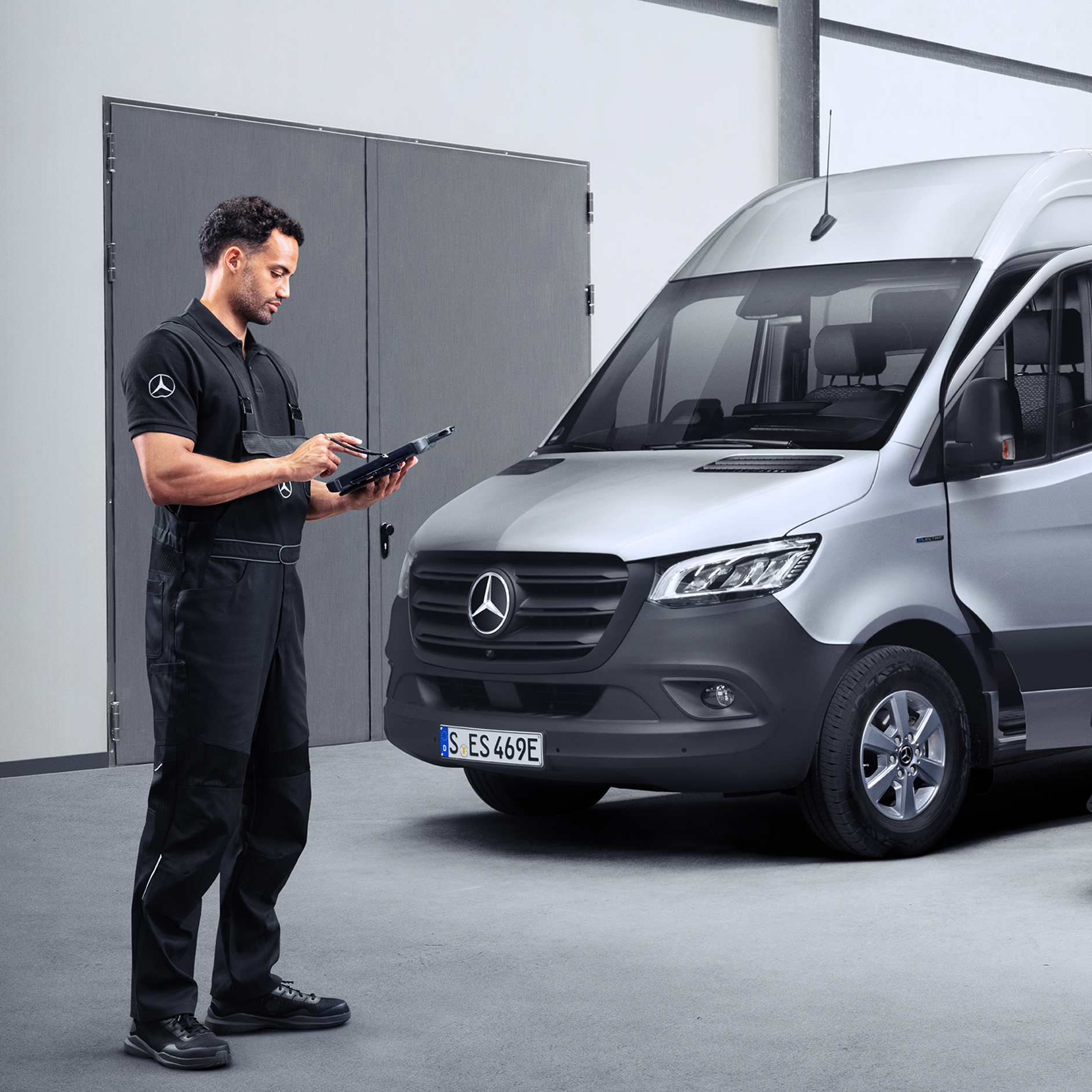 Partner serwisowy Mercedes-Benz | Serwisowanie i przegląd Partner serwisowy Mercedes-Benz patrzy na ekran tabletu, stojąc przed pojazdem Mercedes-Benz eSprinter.