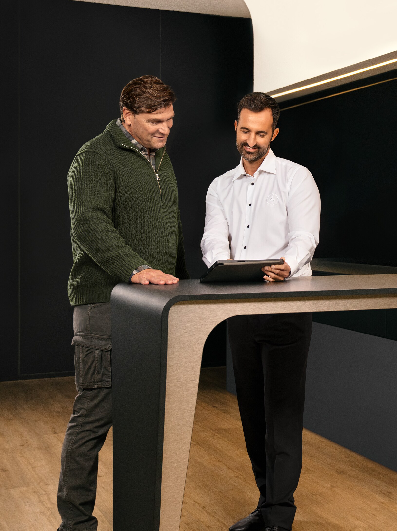 Dwóch mężczyzn konsultuje się nad stołem, patrząc na iPada.