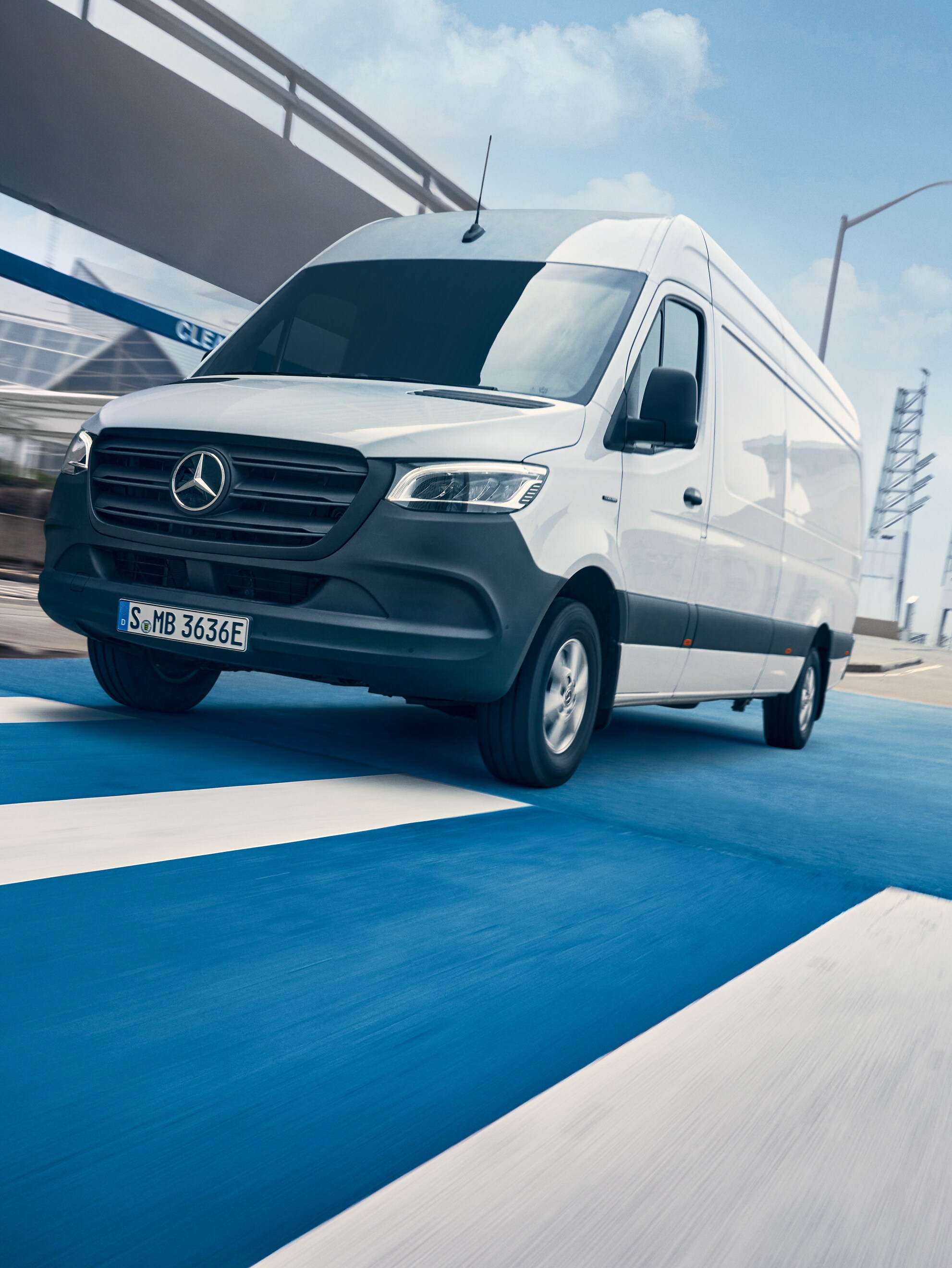 Biały Mercedes-Benz Sprinter jedzie ulicą przez miasto.