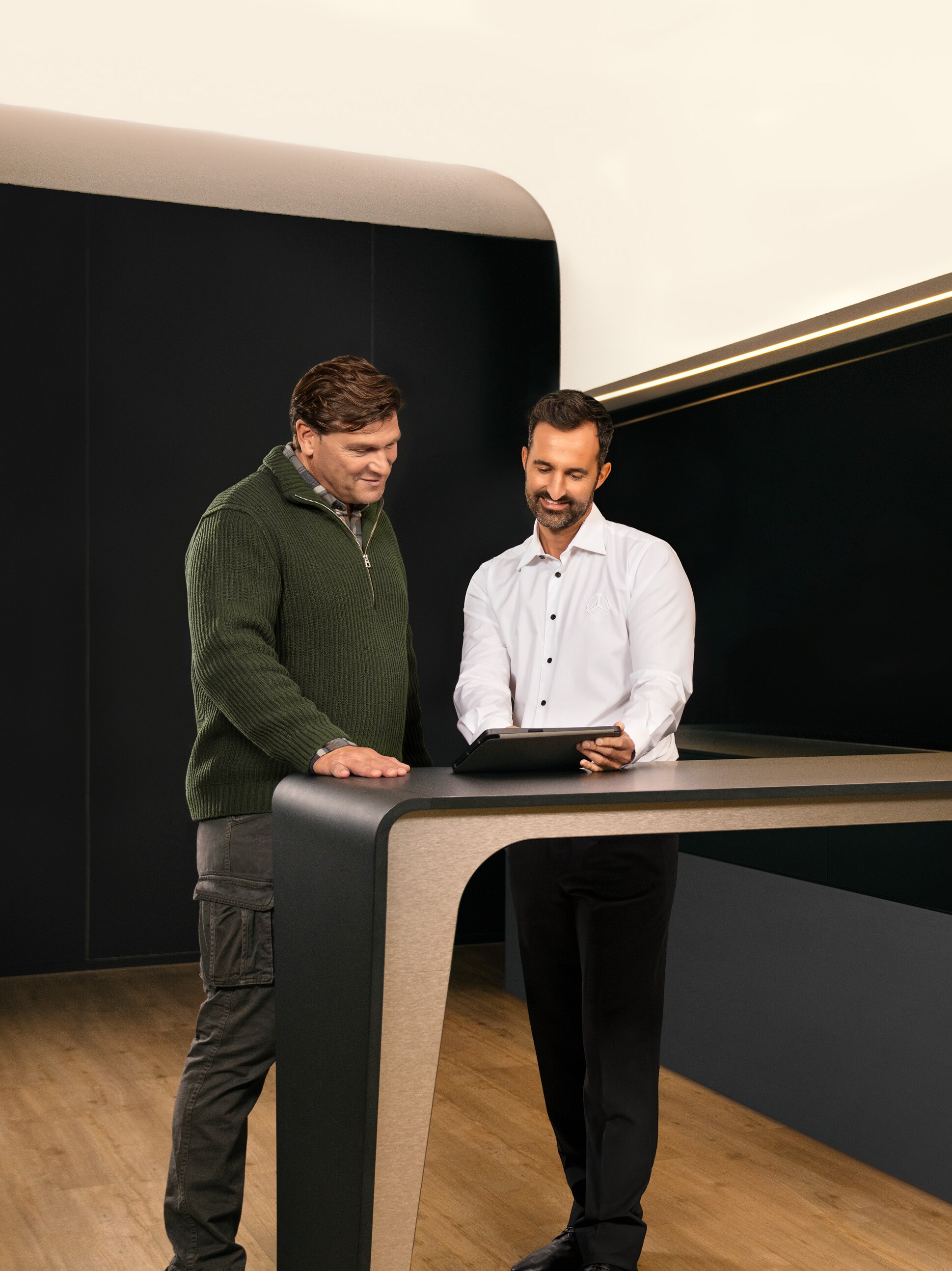 Dwóch mężczyzn omawia usługi Mercedes-Benz dla pojazdów użytkowych nad tabletem.