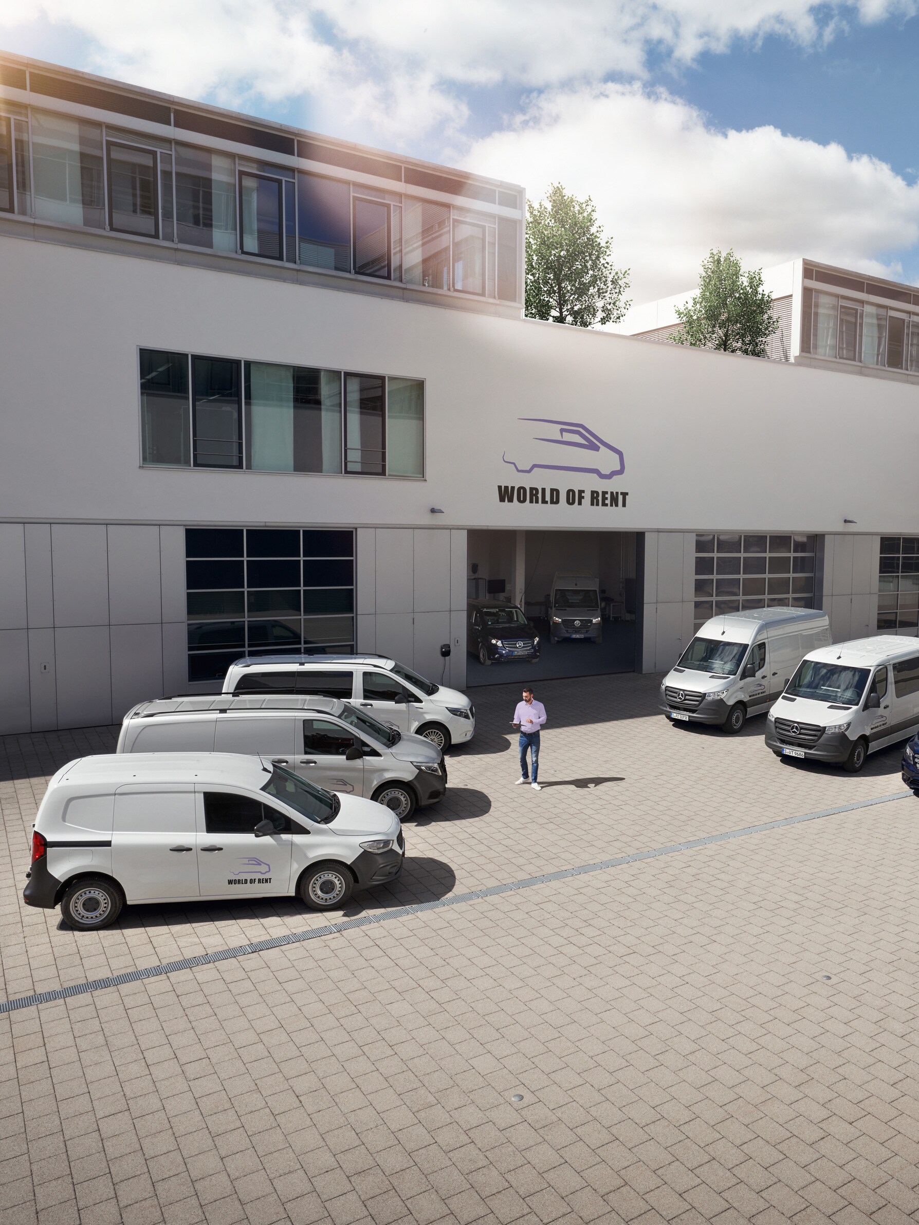 Flota samochodów dostawczych Mercedes-Benz przed budynkiem firmy.