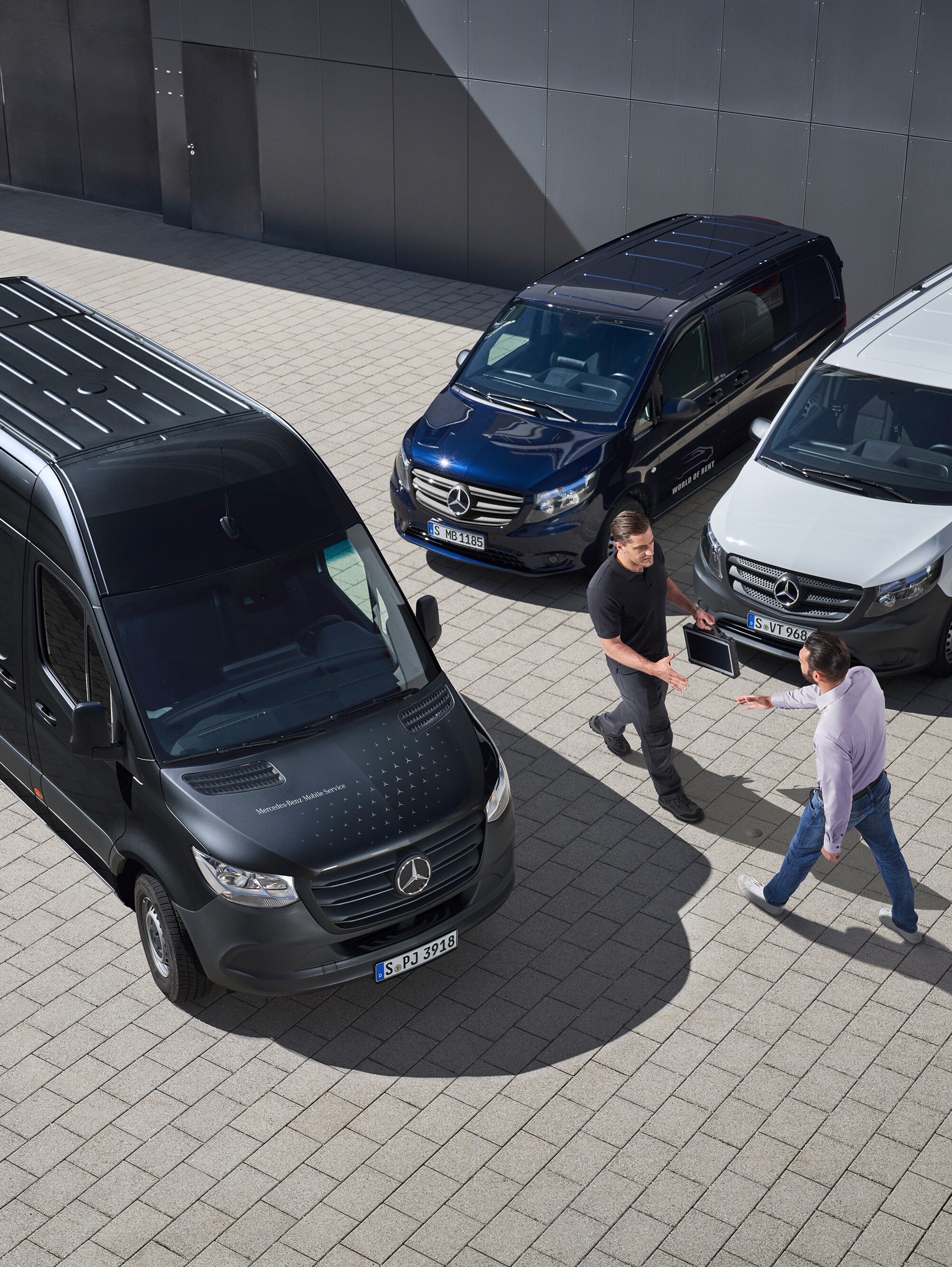 Dwóch mężczyzn wita się pomiędzy samochodami dostawczymi Mercedes-Benz.