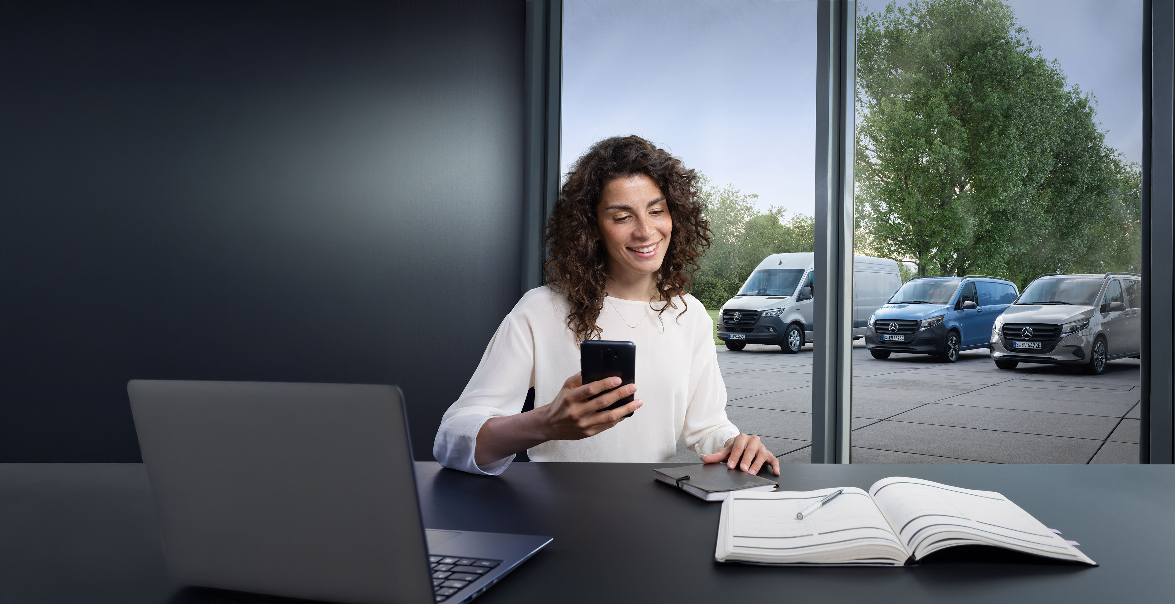 Mercedes-Benz | Naprawa | Wyszukiwanie partnerów serwisowych Klient rozmawia przez telefon przed gamą samochodów dostawczych Mercedes-Benz.