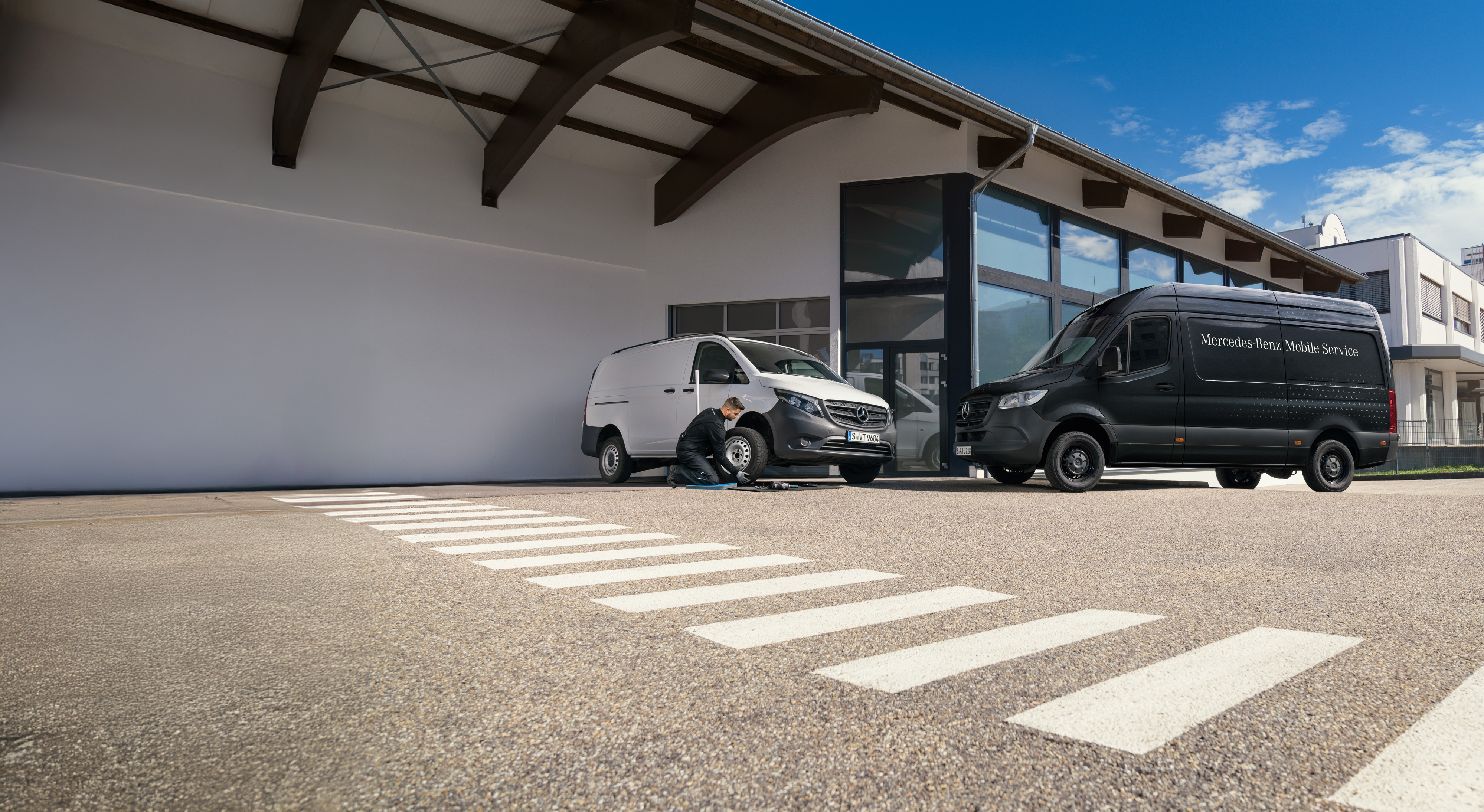 Mercedes-Benz | Serwis mobilny | Zamów usługę Mechanik wymienia oponę w białym samochodzie dostawczym Mercedes-Benz Vito na parkingu.