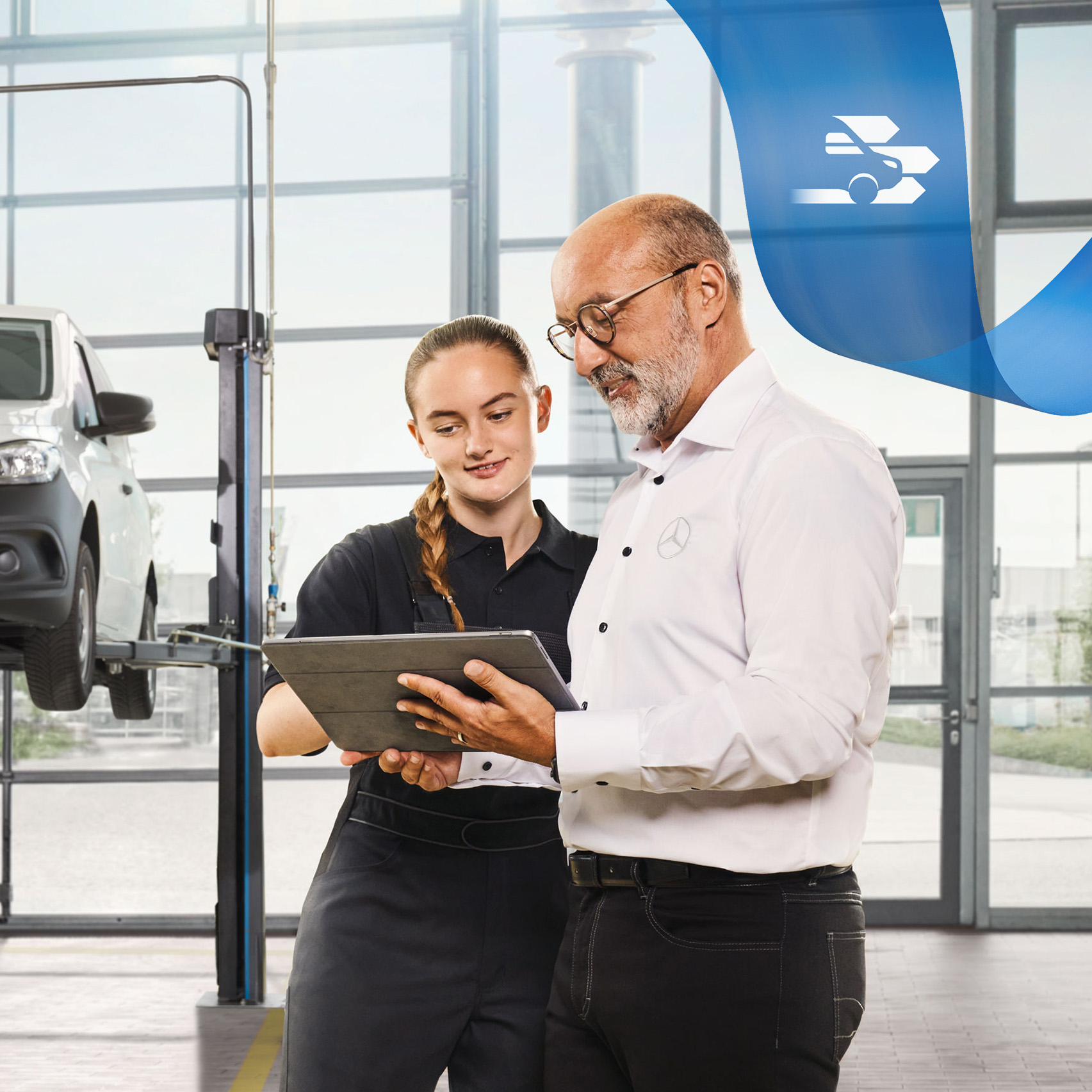 Mercedes-Benz | Serwisowanie Dwóch pracowników omawia obsługę pojazdu użytkowego dla samochodu dostawczego Mercedes-Benz na podnośniku w warsztacie.
