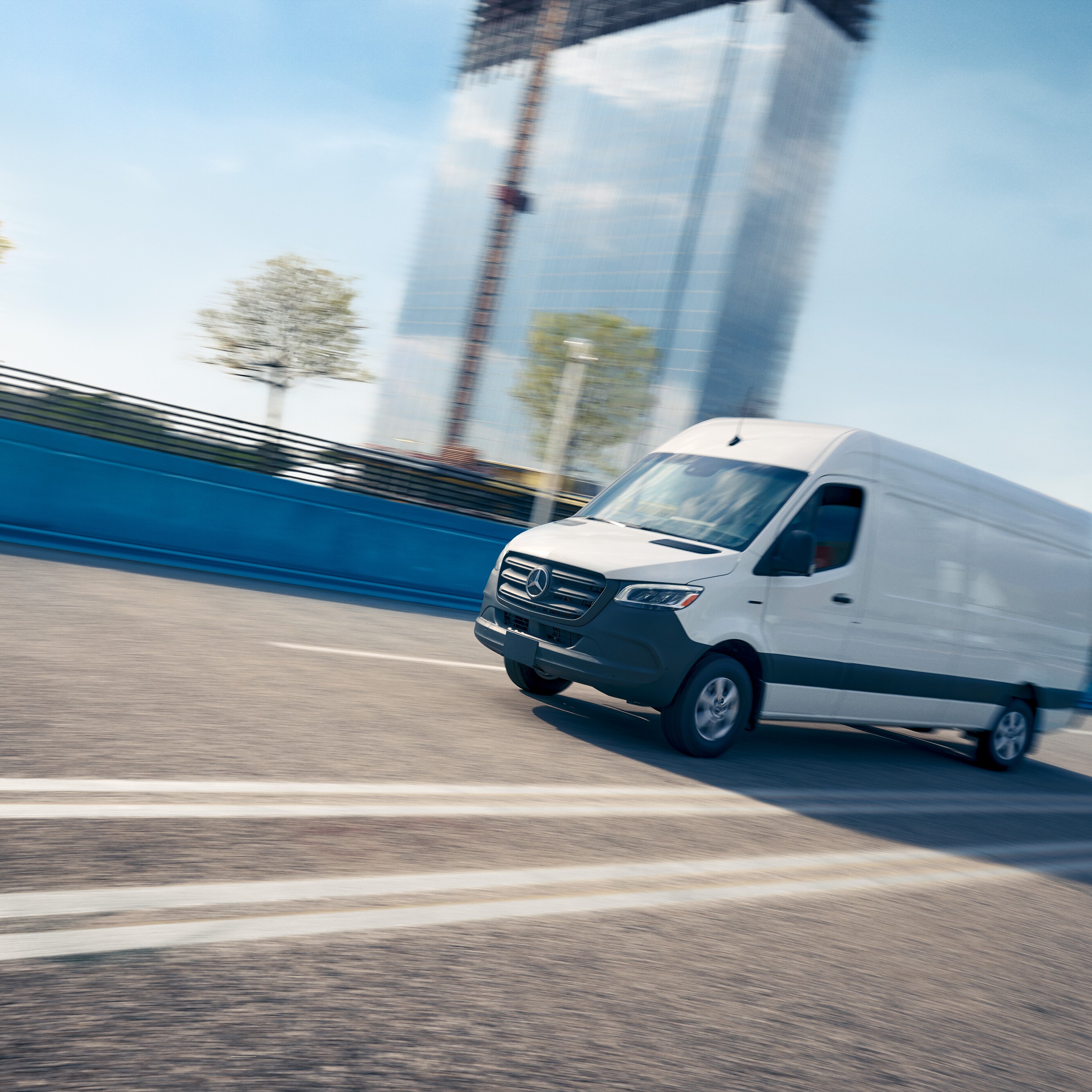 Biały samochód dostawczy jadący drogą, reklamujący aplikację serwisową Mercedes-Benz umożliwiającą rezerwację wizyt online.