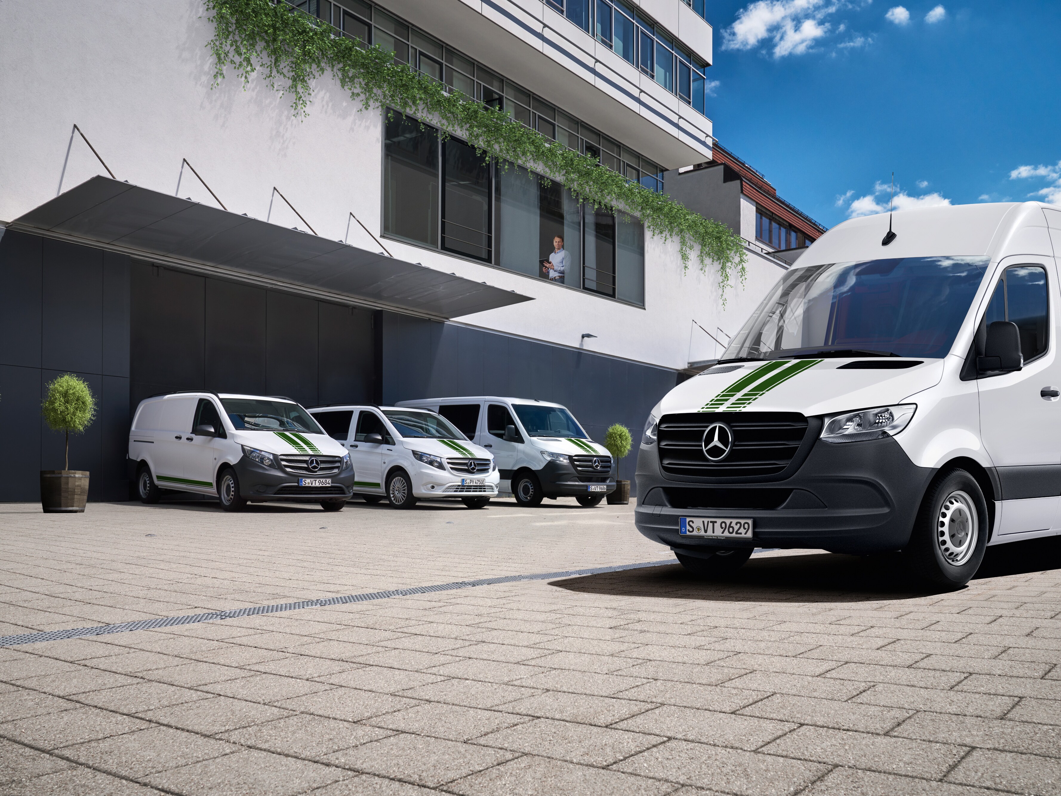 Flota samochodów dostawczych Mercedes-Benz przed budynkiem.