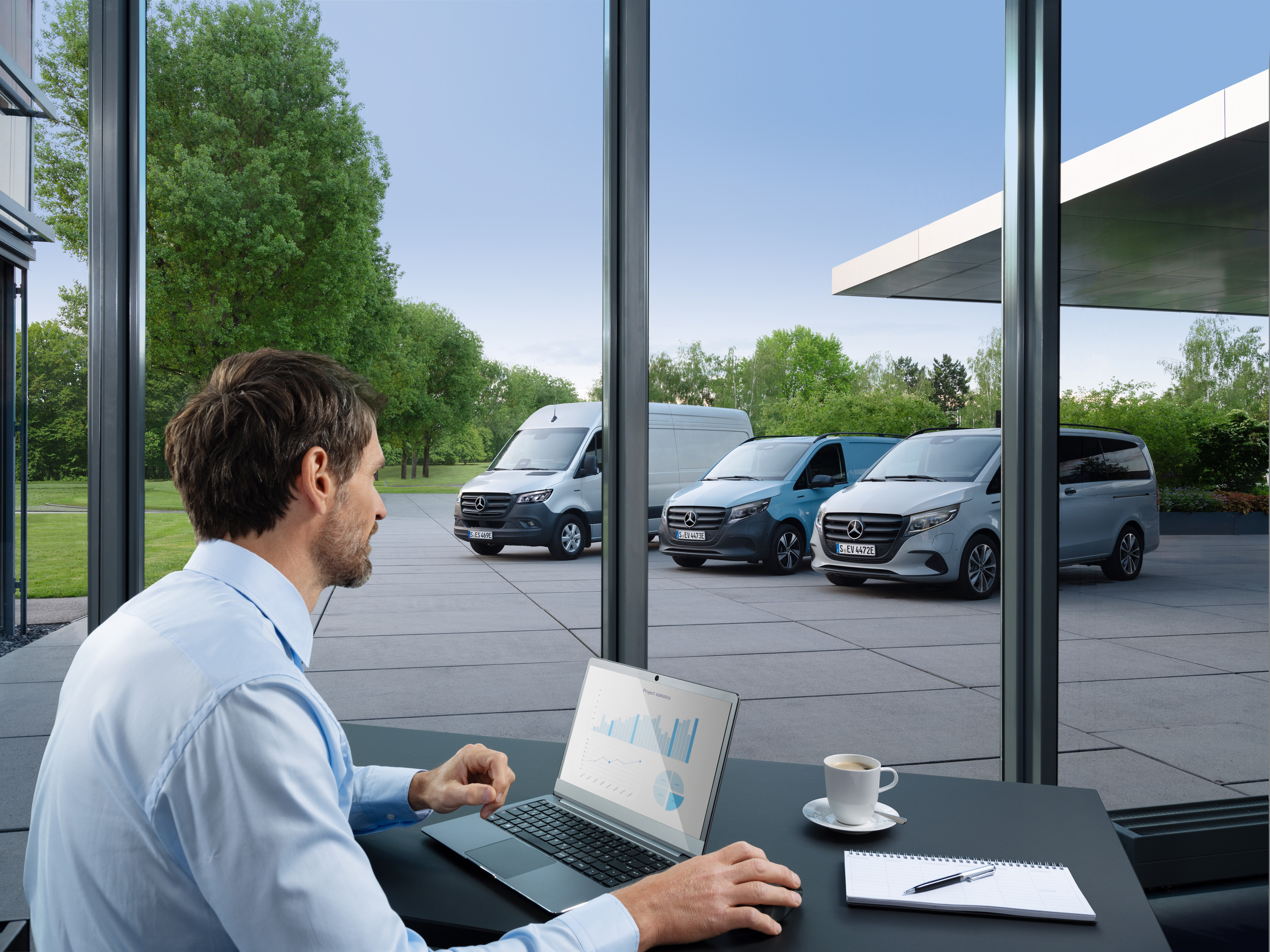 Mercedes-Benz | Technologia samochodów dostawczych | Van Uptime Monitor Mężczyzna monitoruje flotę zaparkowanych samochodów dostawczych Mercedes-Benz za pomocą laptopa.