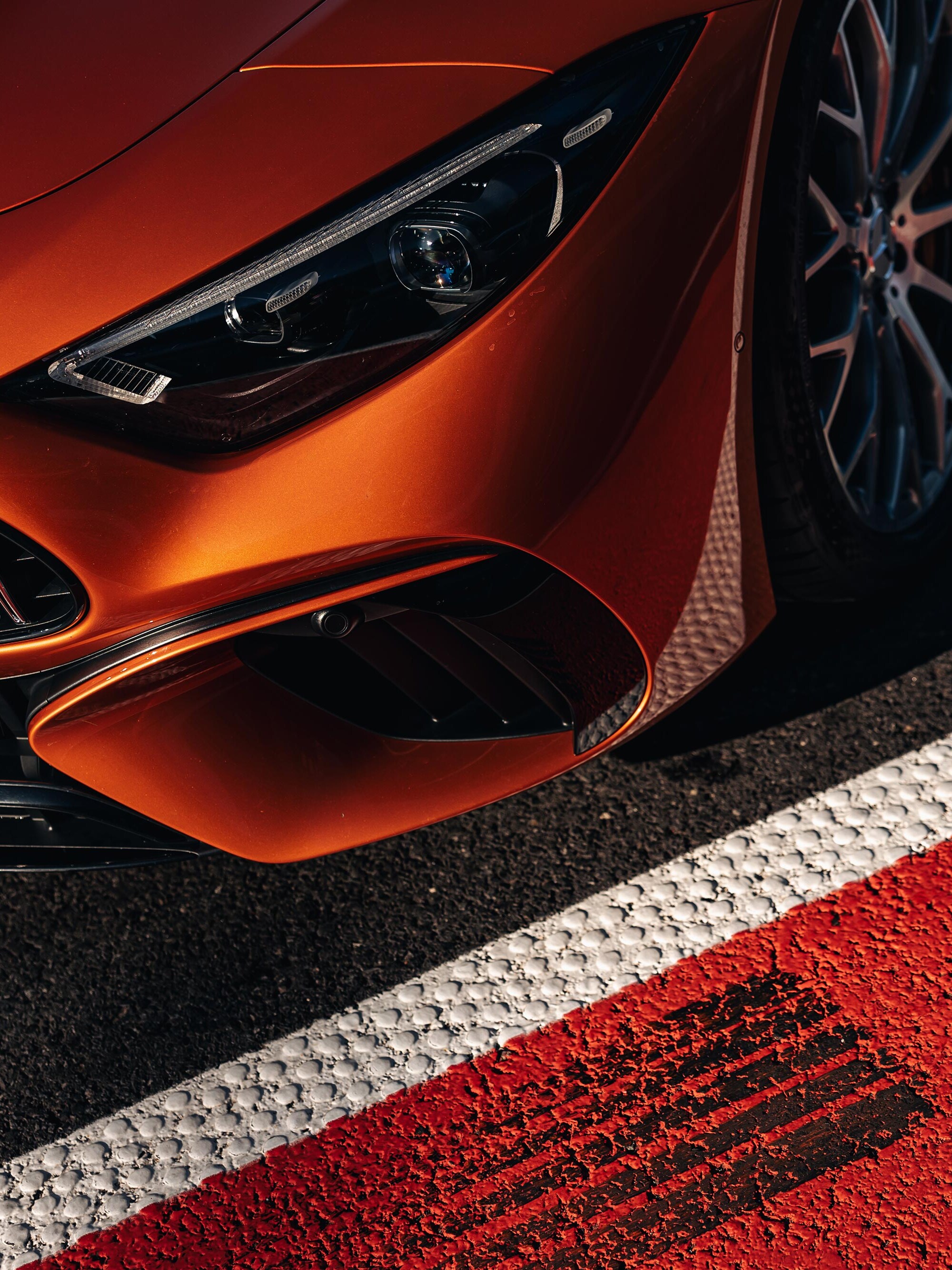 Pomarańczowy Mercedes-AMG zaparkowany na torze wyścigowym.