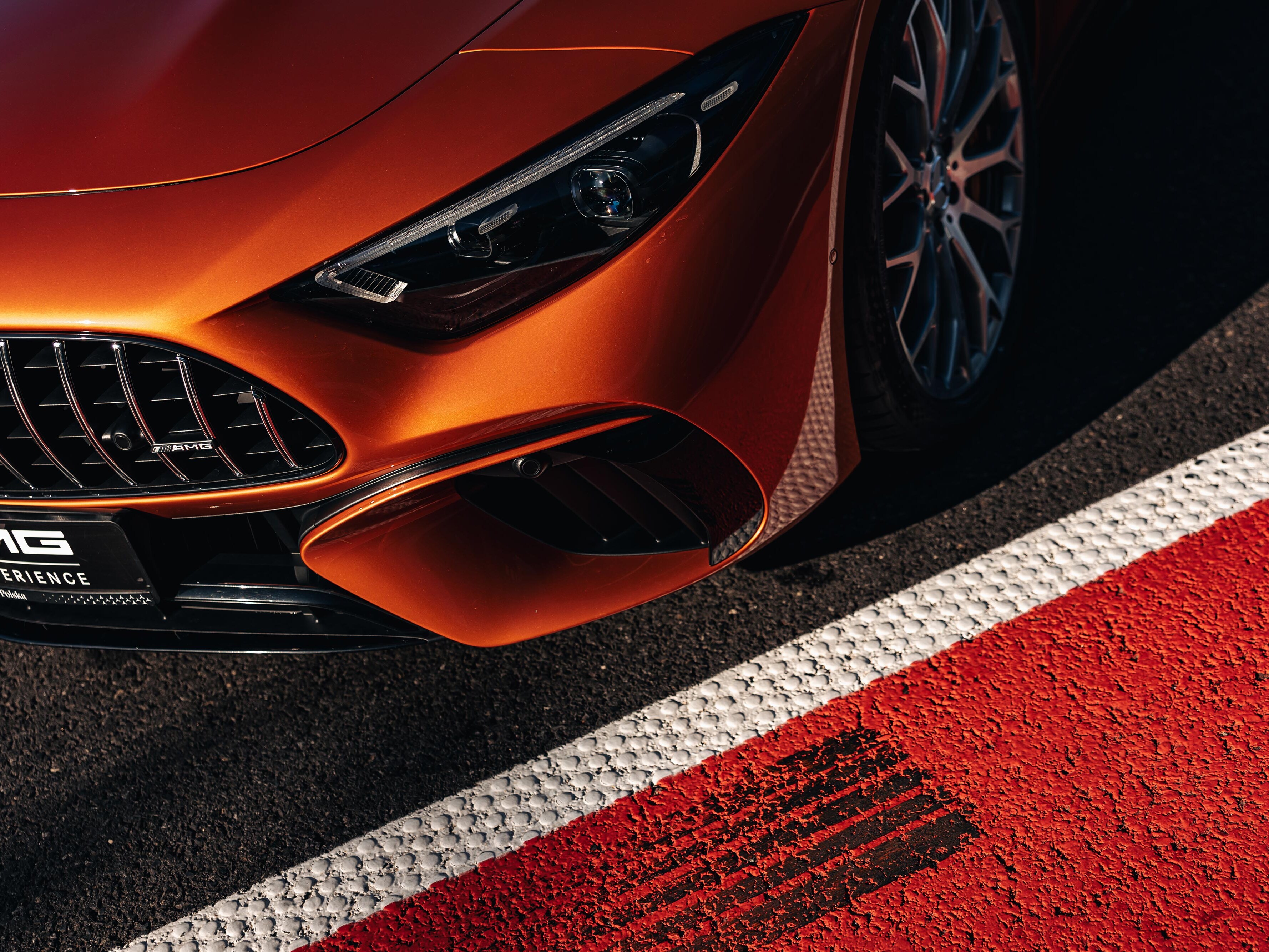 Pomarańczowy Mercedes-AMG zaparkowany na torze wyścigowym.