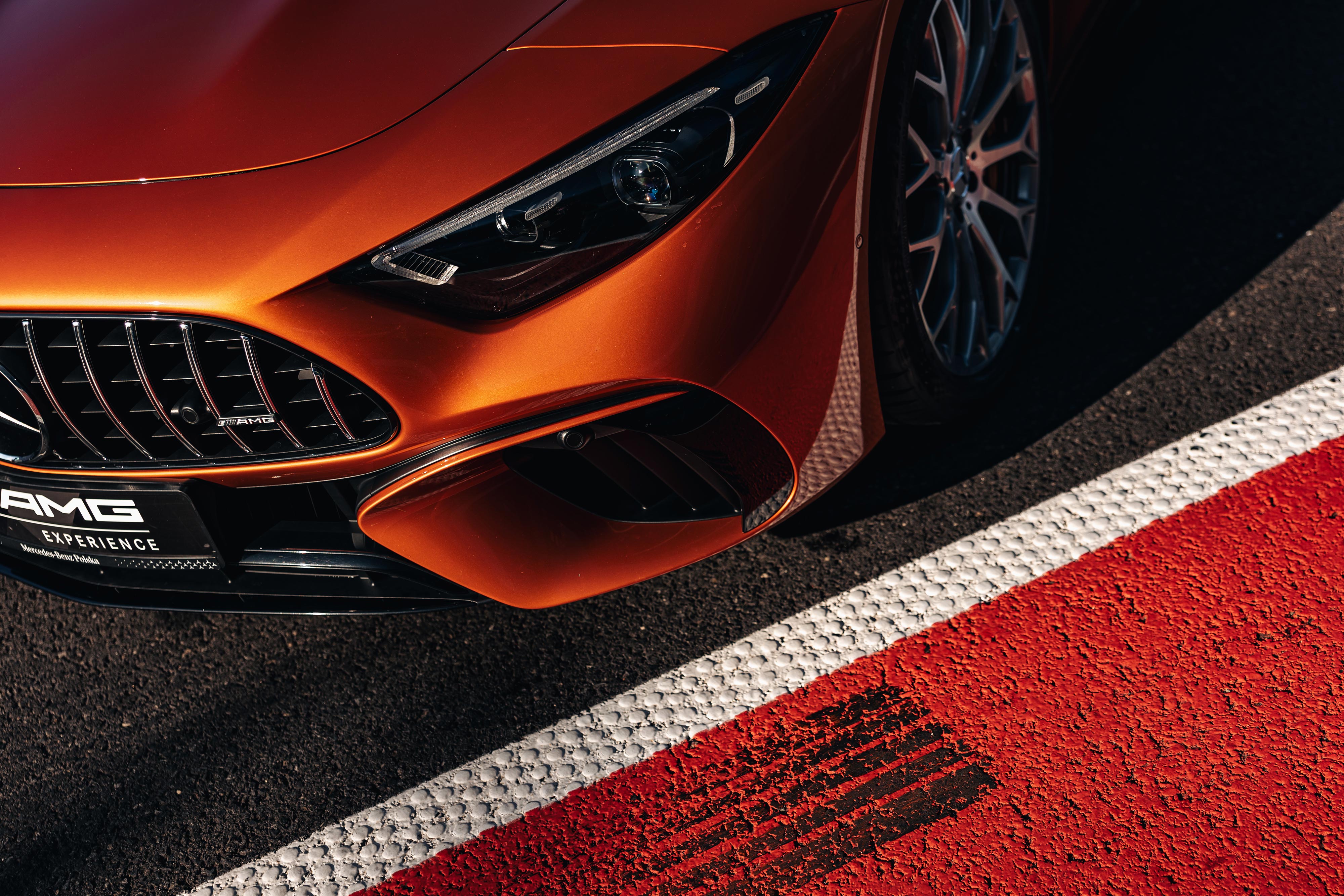 AMG Experience | Mercedes-Benz Pomarańczowy Mercedes-AMG zaparkowany na torze wyścigowym.