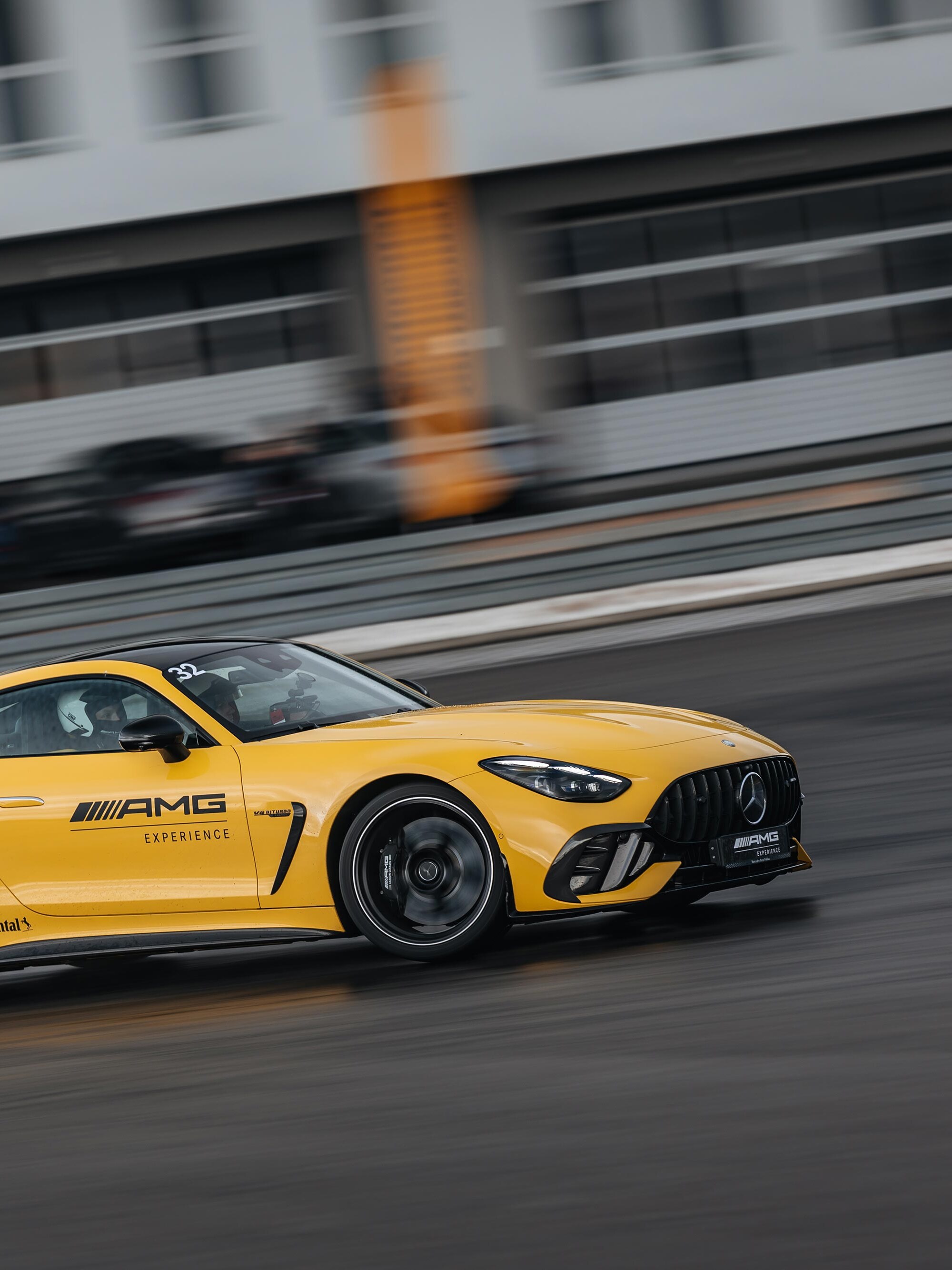 Żółty Mercedes-AMG GT Coupé z logo AMG Experience na drzwiach.