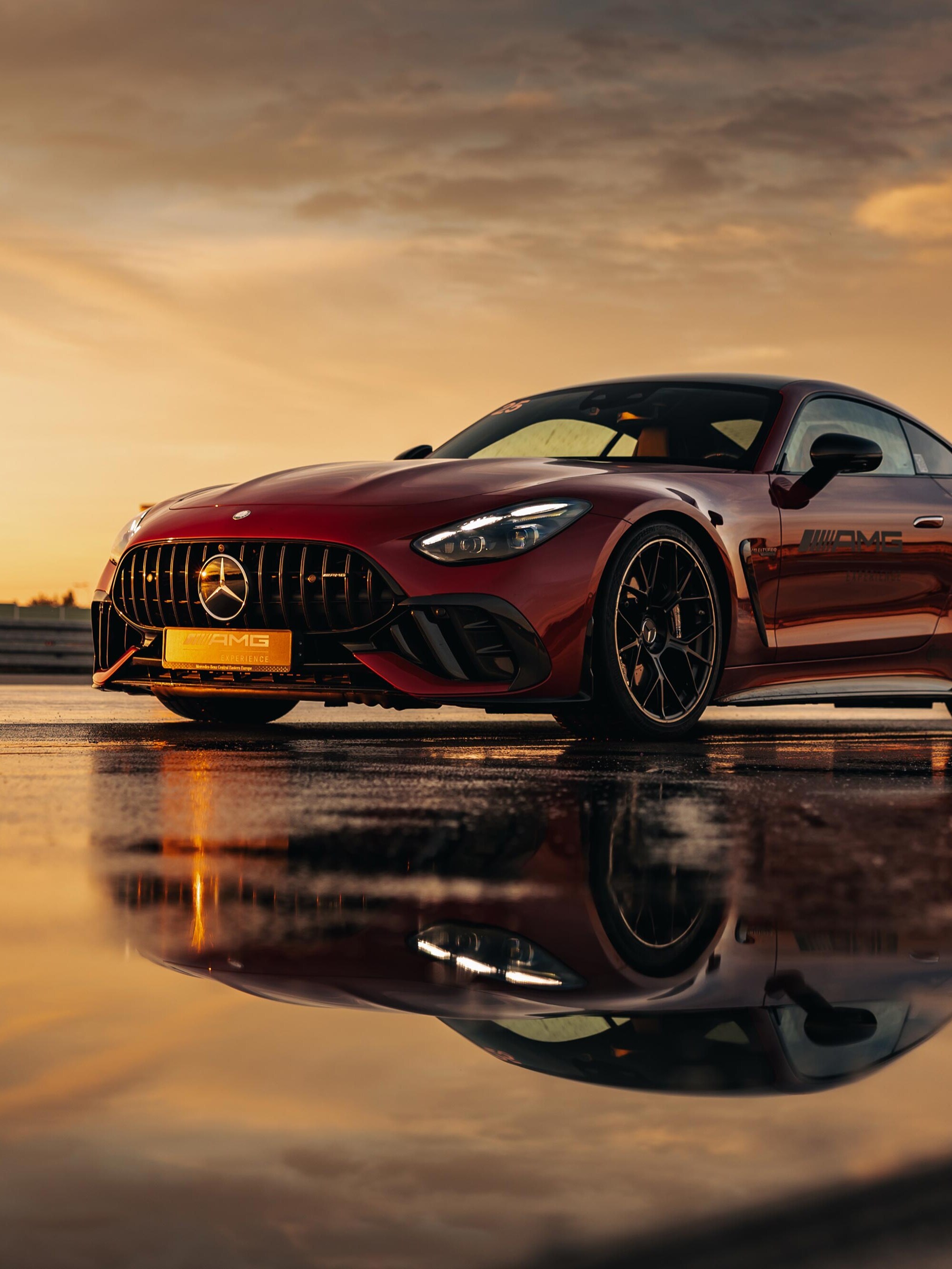 Czerwony Mercedes-AMG GT Coupé z logo AMG Experience na drzwiach.