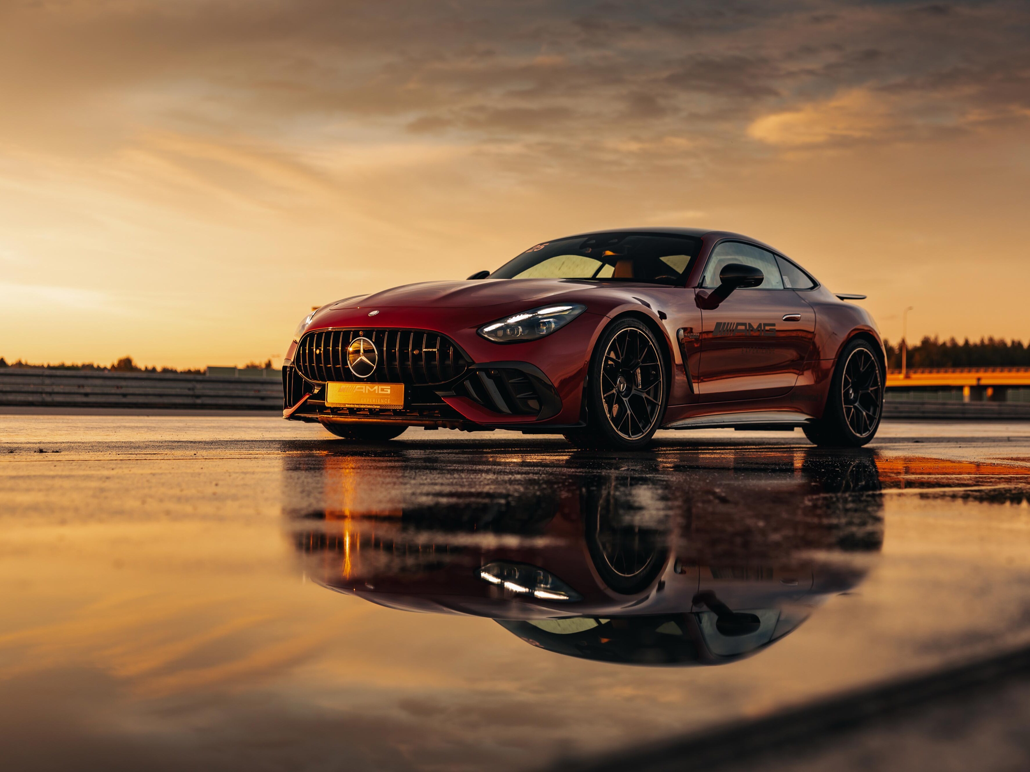 Czerwony Mercedes-AMG GT Coupé z logo AMG Experience na drzwiach.