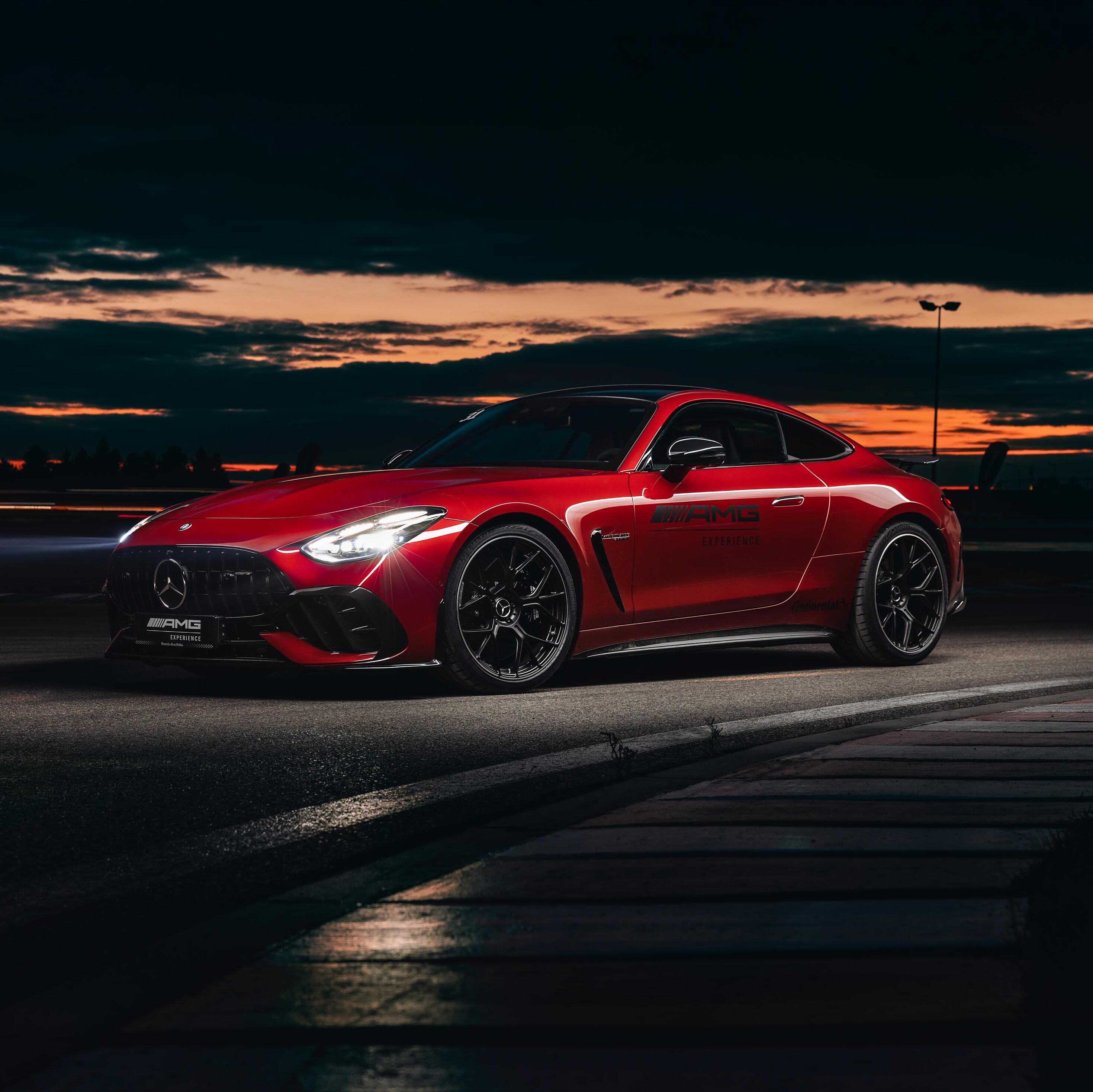 Czerwony Mercedes-AMG GT Coupé z logo AMG Experience na drzwiach.