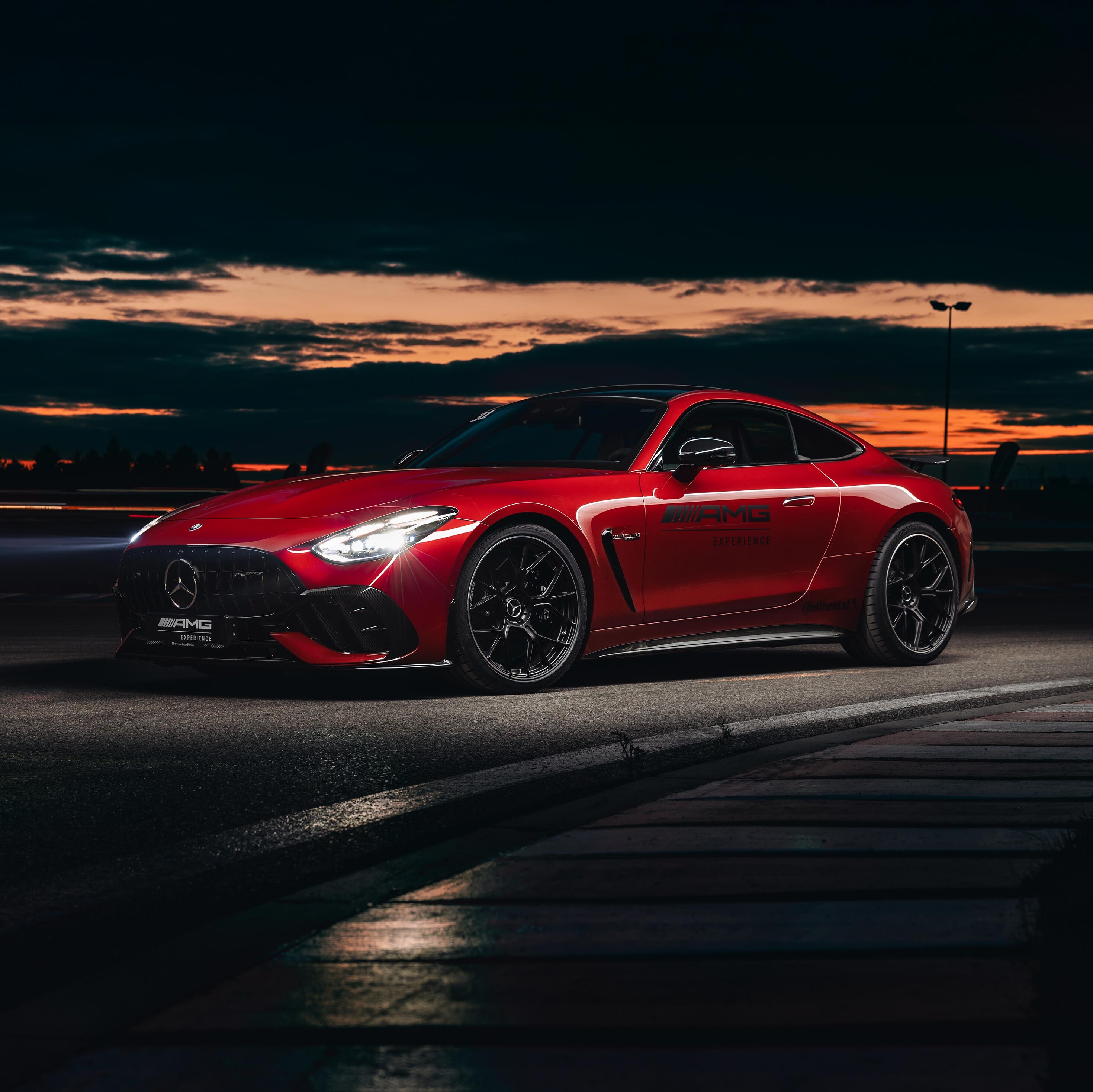 Czerwony Mercedes-AMG GT Coupé z logo AMG Experience na drzwiach.