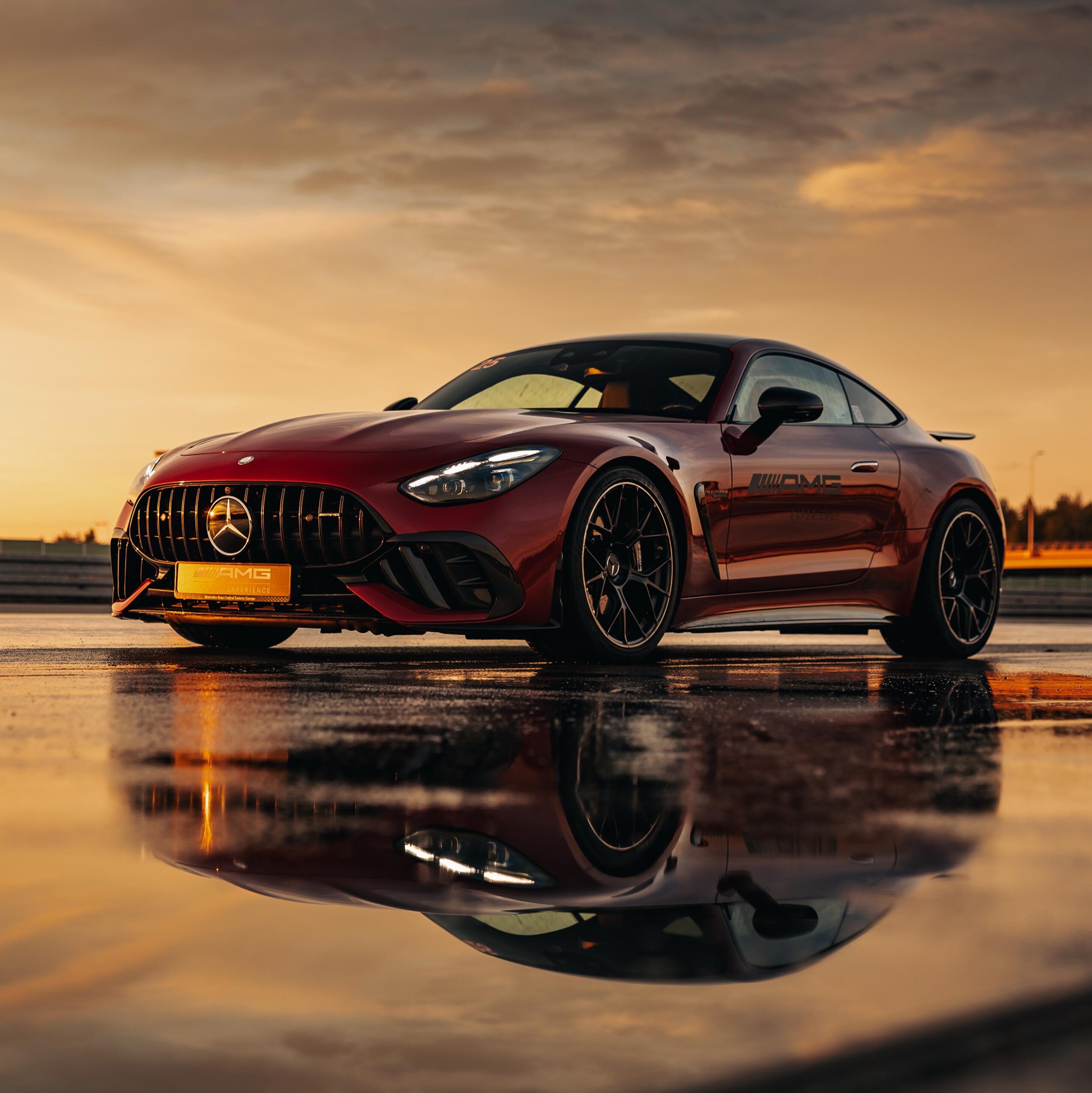 Czerwony Mercedes-AMG GT Coupé z logo AMG Experience na drzwiach.