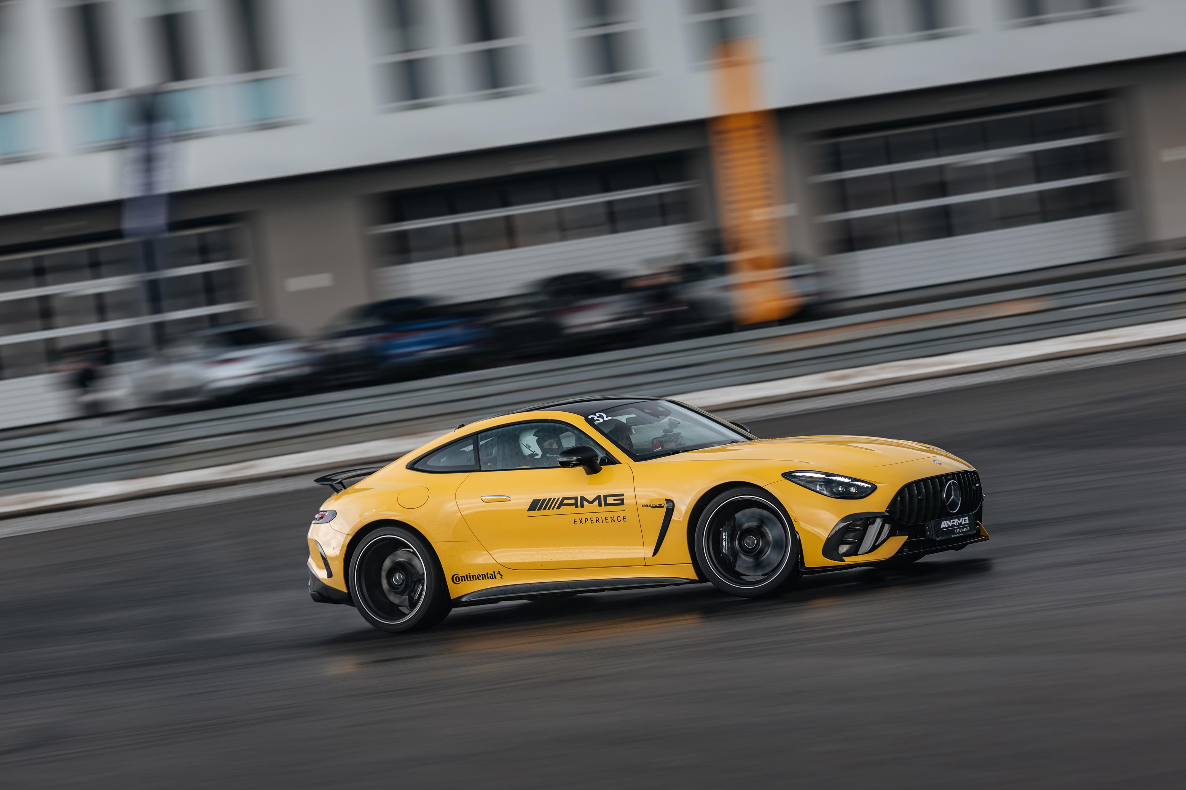 AMG Experience on Track INTENSIVE | Mercedes-Benz Żółty Mercedes-AMG GT Coupé z logo AMG Experience na drzwiach jedzie na torze wyściegowym.