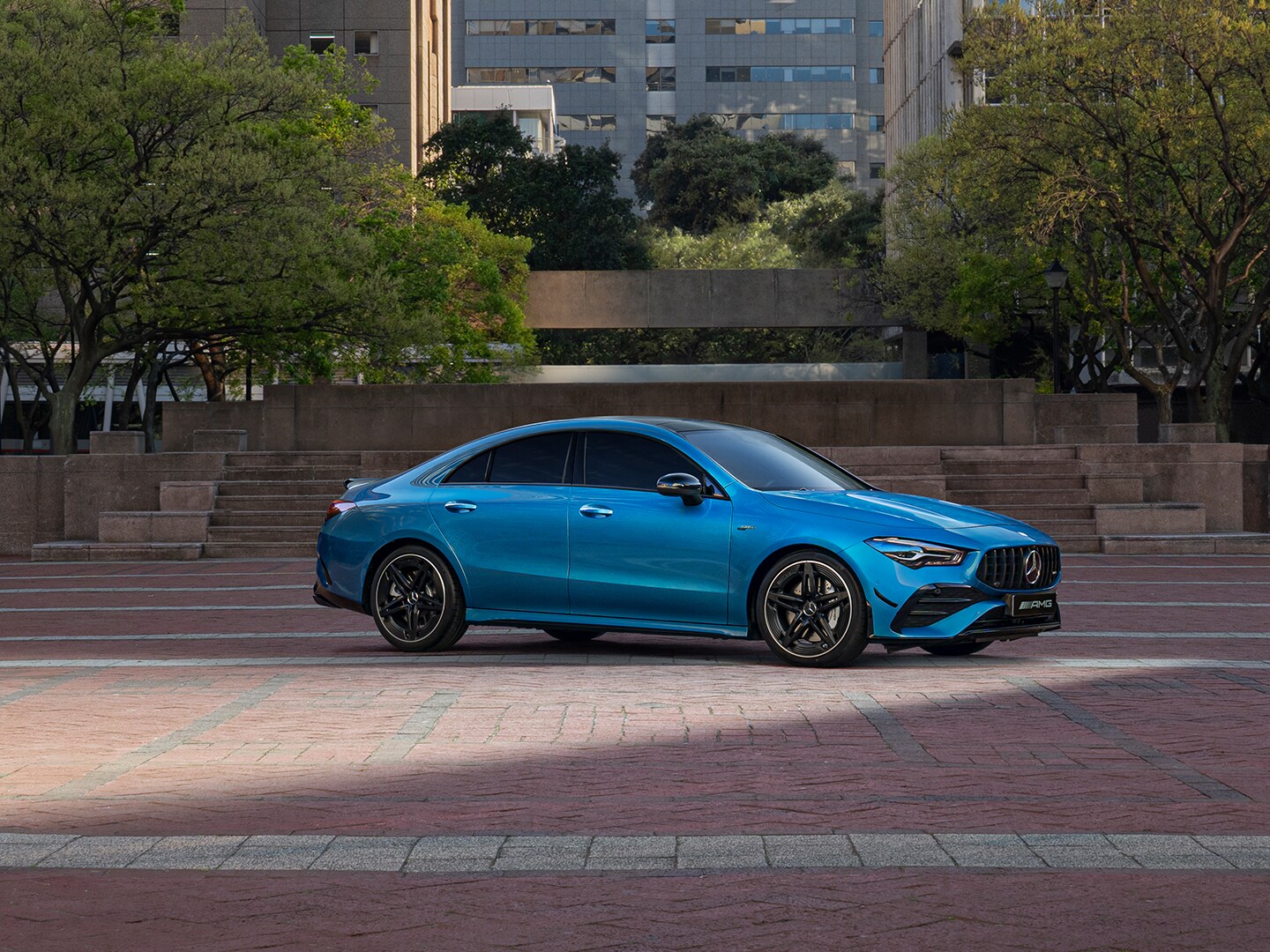 Mercedes CLA 35 4MATIC zaparkowy przed schodami prowadzącymi do budynków biurowych..