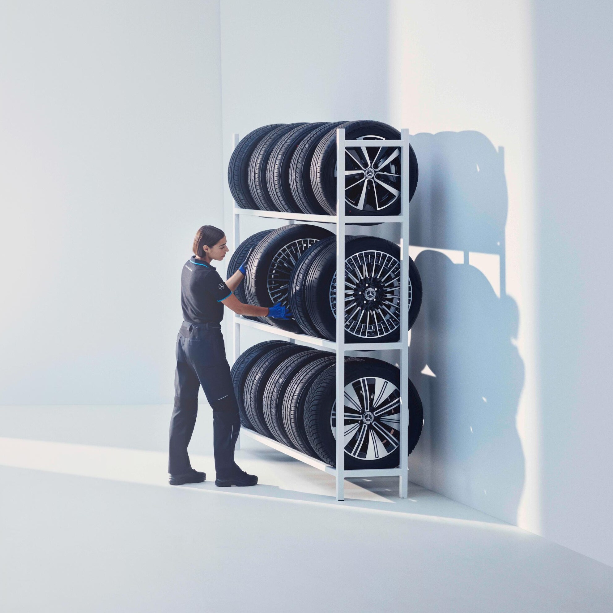 Technik Mercedes-Benz układa opony Mercedes-Benz Original na półce.