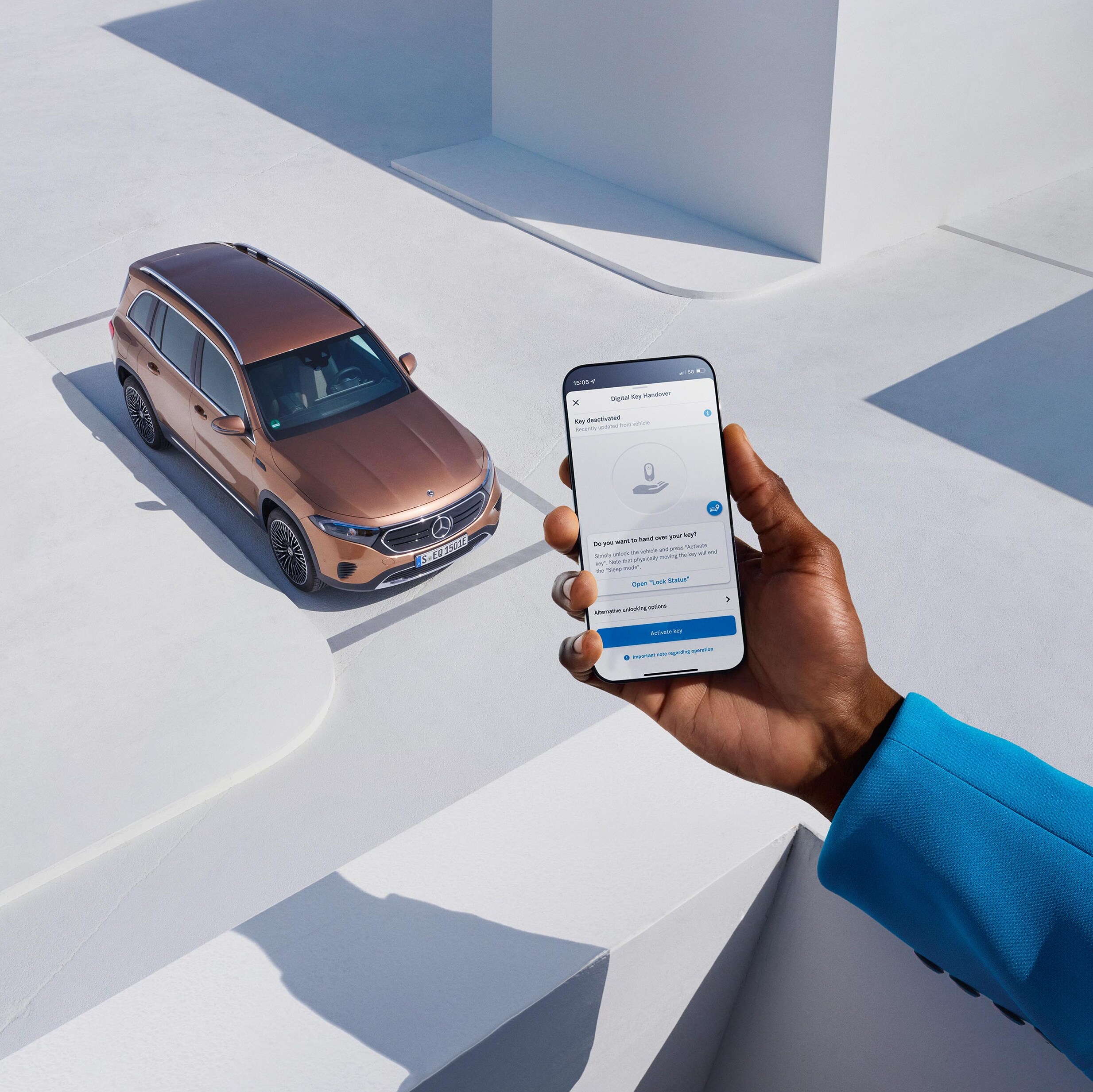 Kierowca Mercedesa trzyma w dłoni smartfon z aplikacją Mercedes-Benz.