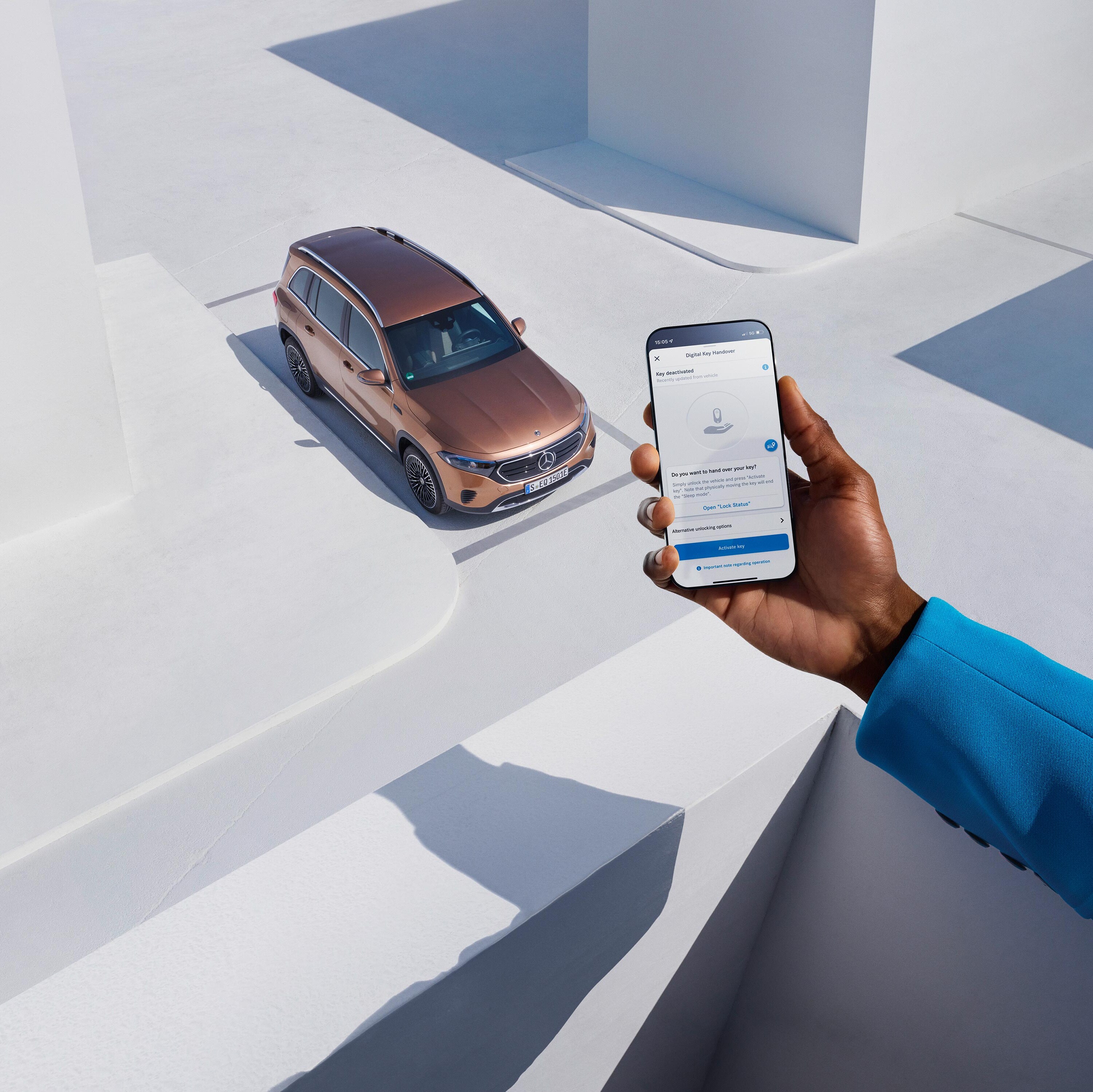 Kierowca Mercedesa trzyma w dłoni smartfon z aplikacją Mercedes-Benz.