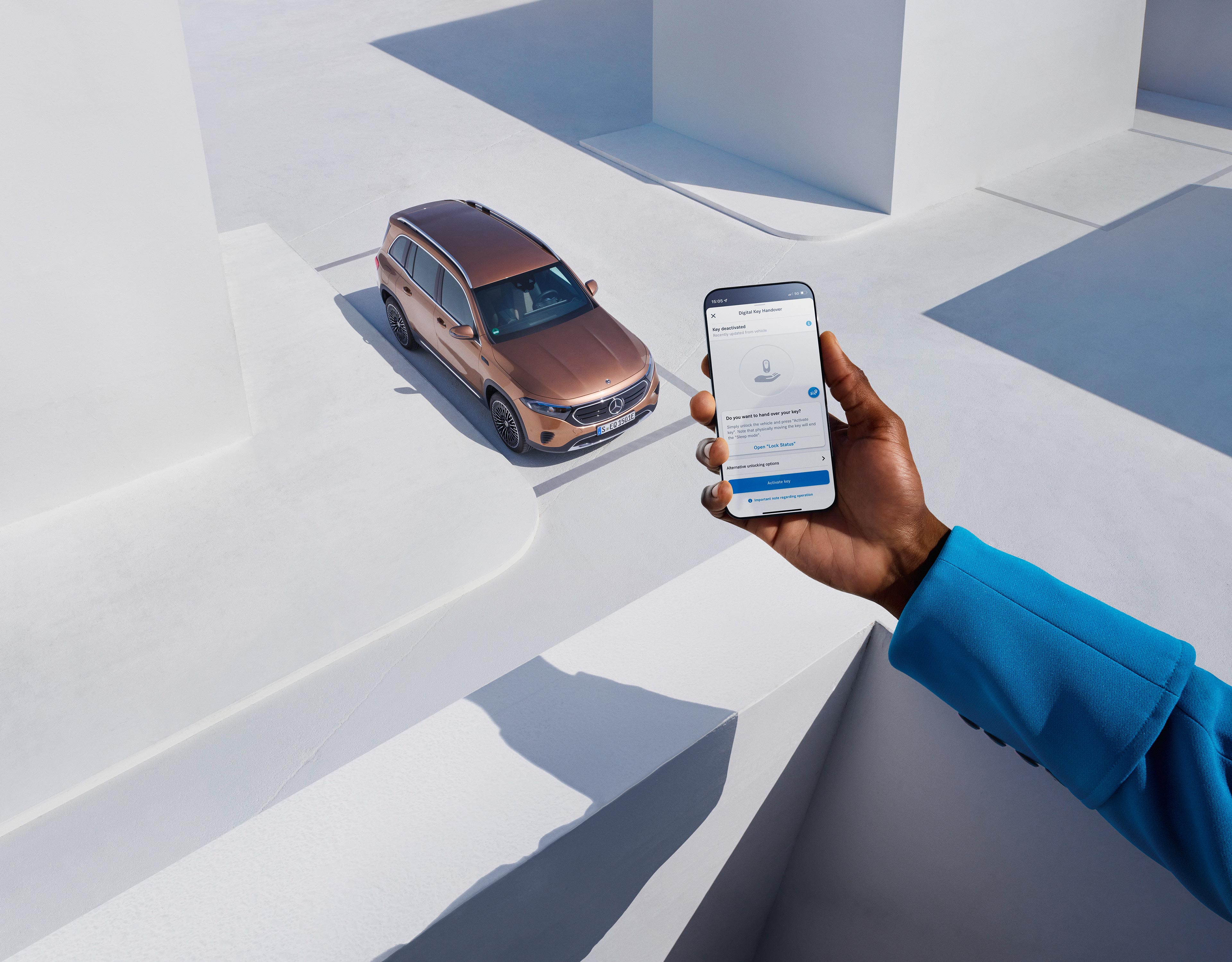 Kierowca Mercedesa trzyma w dłoni smartfon z aplikacją Mercedes-Benz.