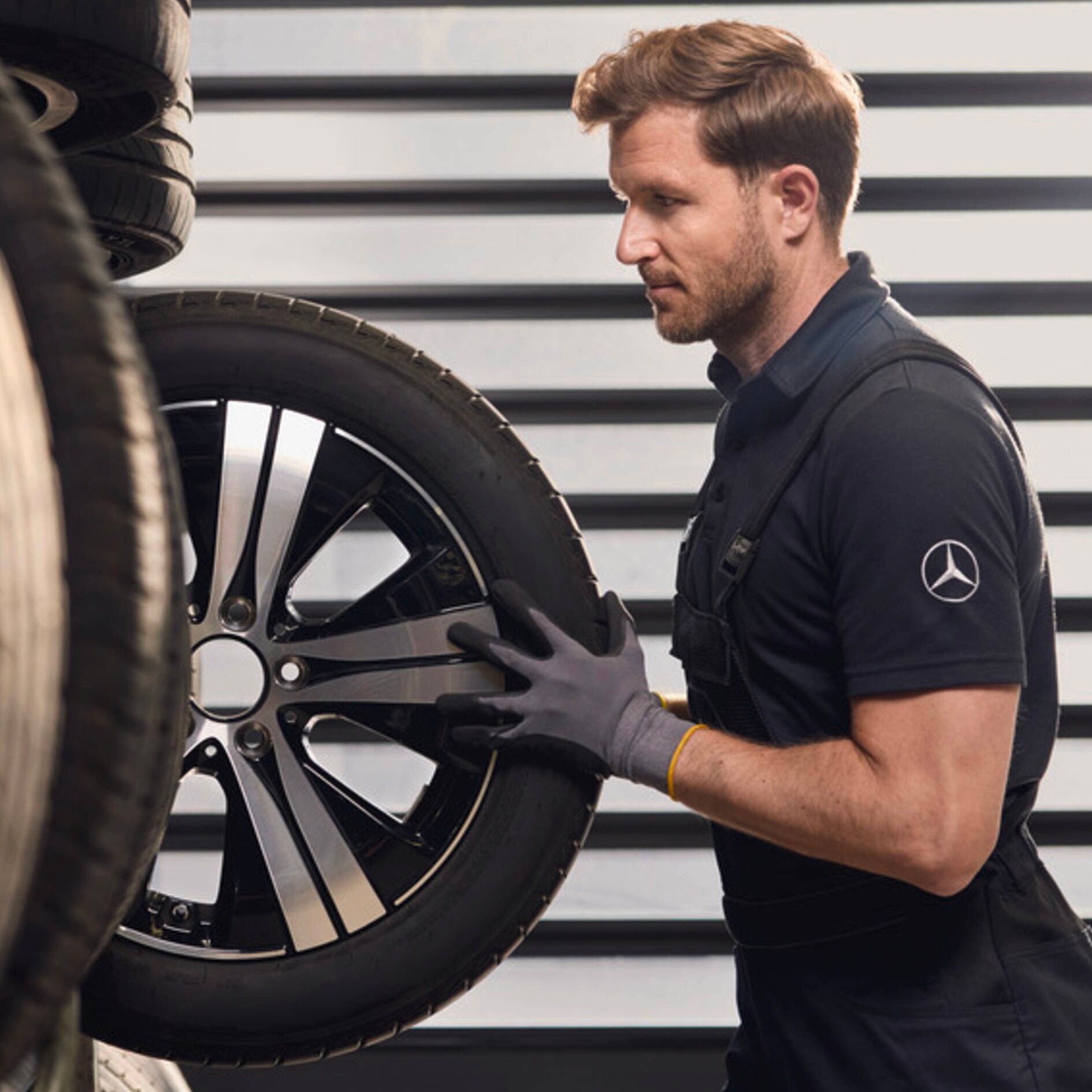 Pracownik serwisu Mercedes-Benz zdejmuje z regału koło do Mercedesa.