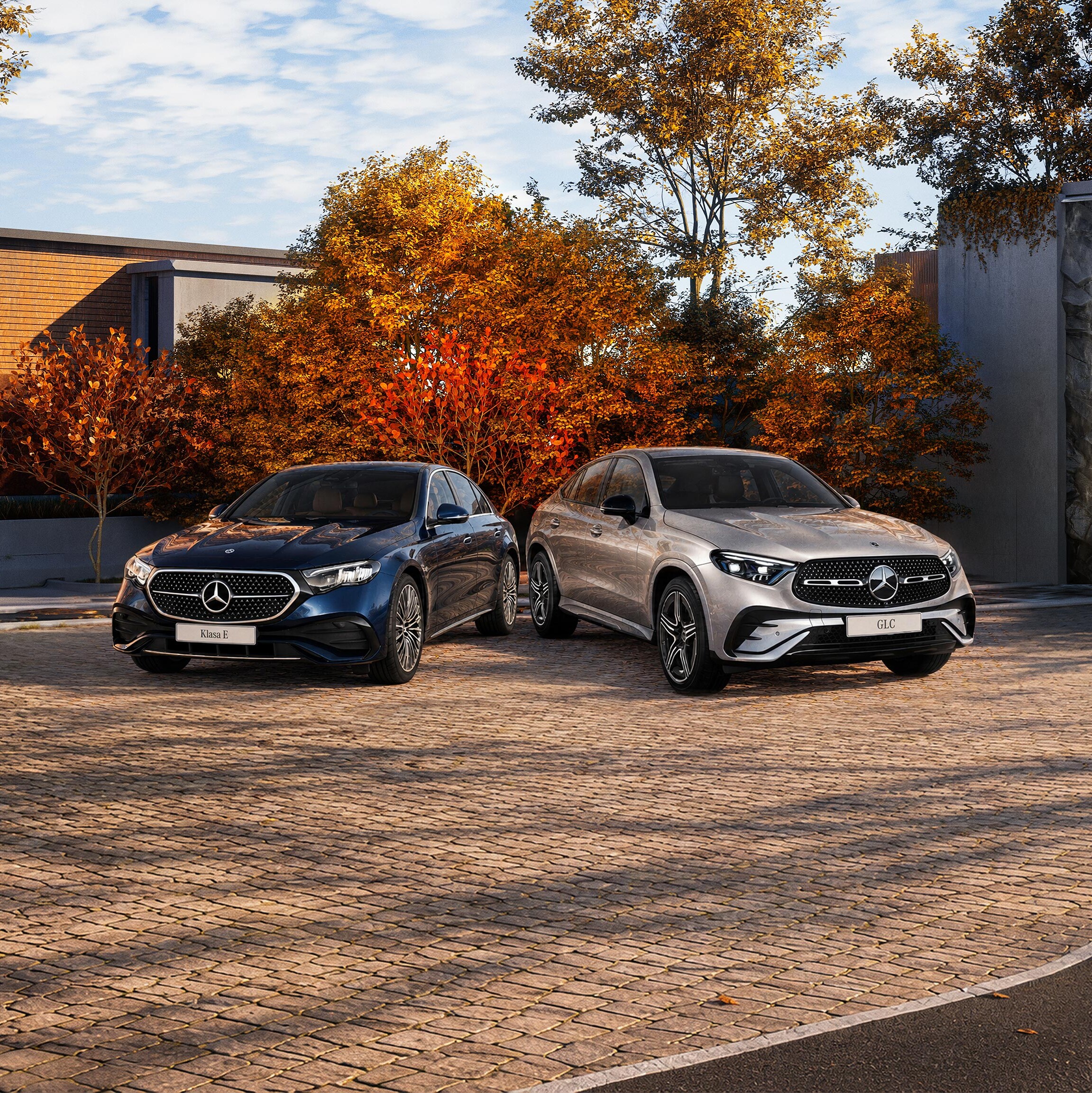 Mercedes-Benz GLC oraz Klasa E Limuzyna zaparkowane na parkingu wśród jesiennych drzew.