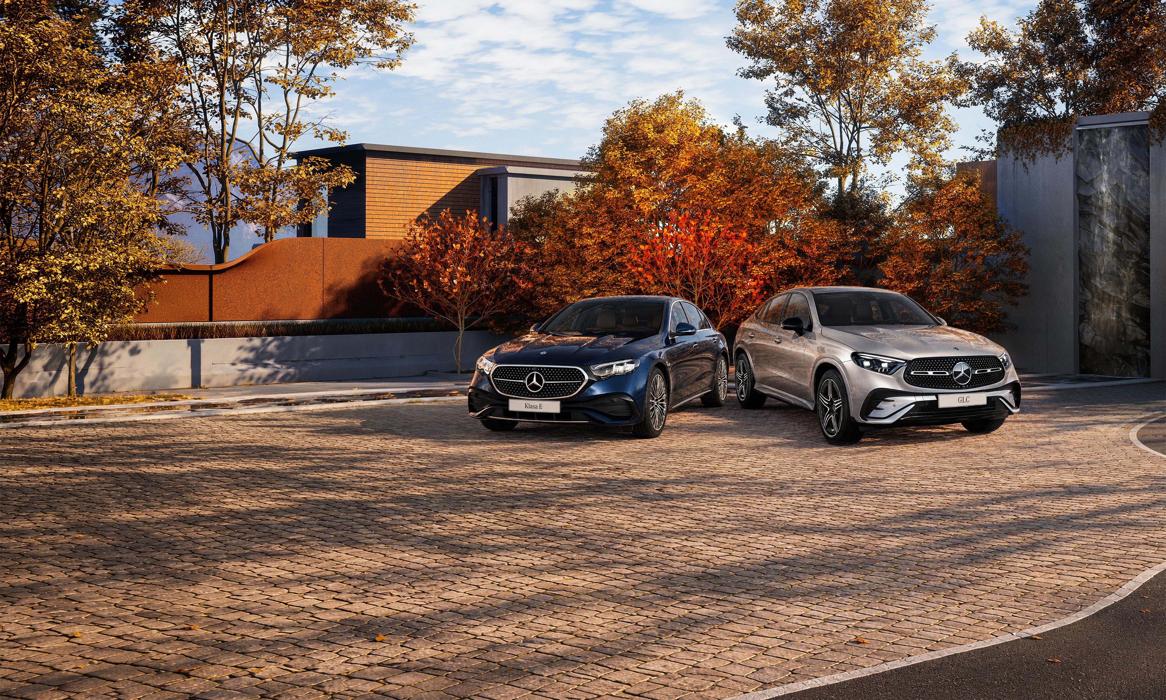 Powitaj jesień z Mercedes-Benz Mercedes-Benz GLC oraz Klasa E Limuzyna zaparkowane na parkingu wśród jesiennych drzew.