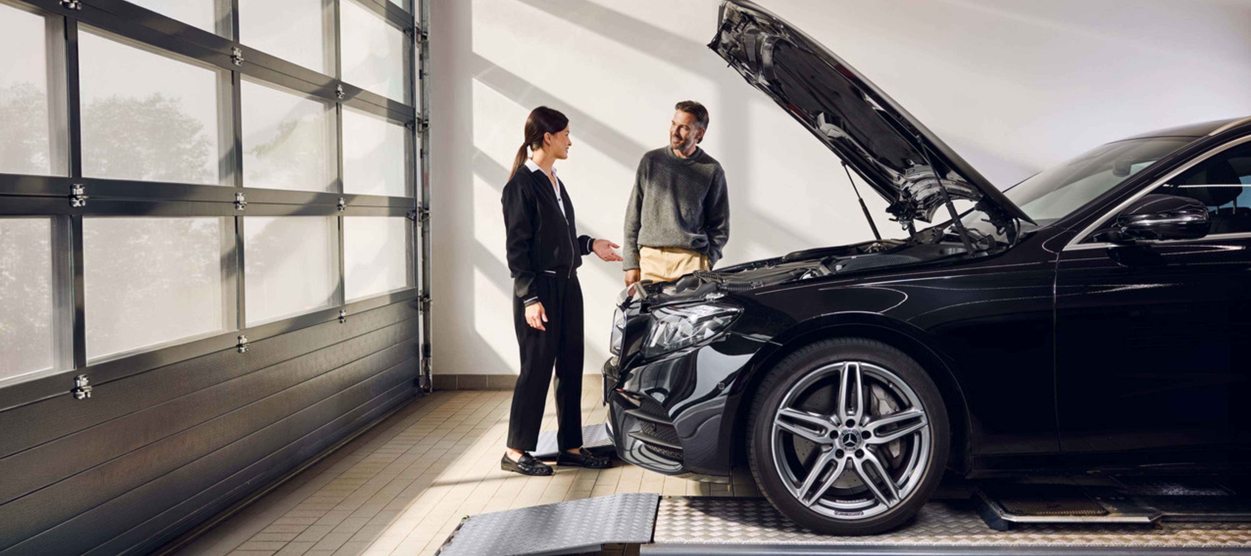 Przegląd zimowy | Mercedes-Benz Mężczyzna rozmawiający z pracownicą serwisu Mercedes-Benz.