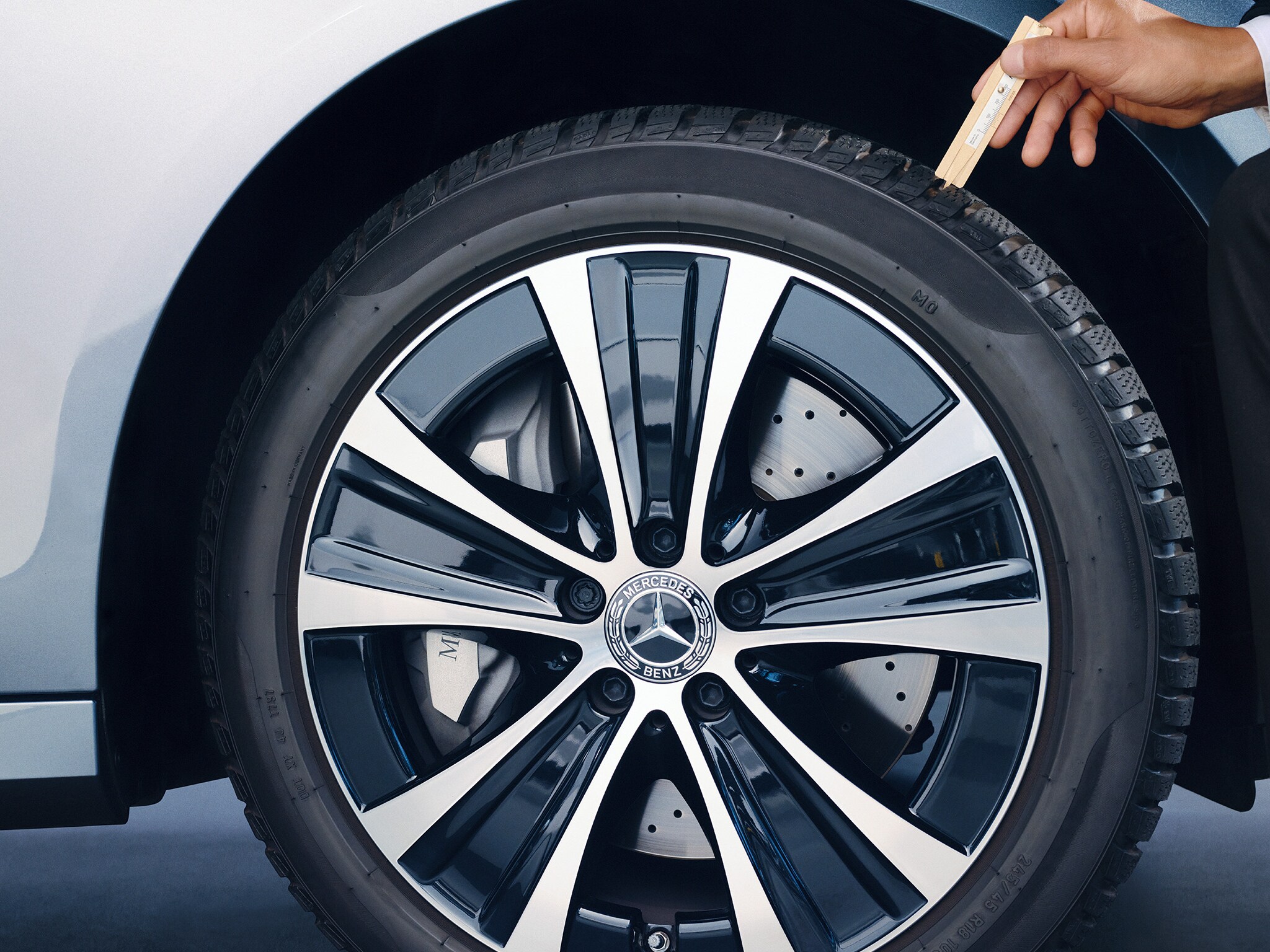 Pracownik serwisu sprawdza głębokość bierznika w oponie Mercedesa.