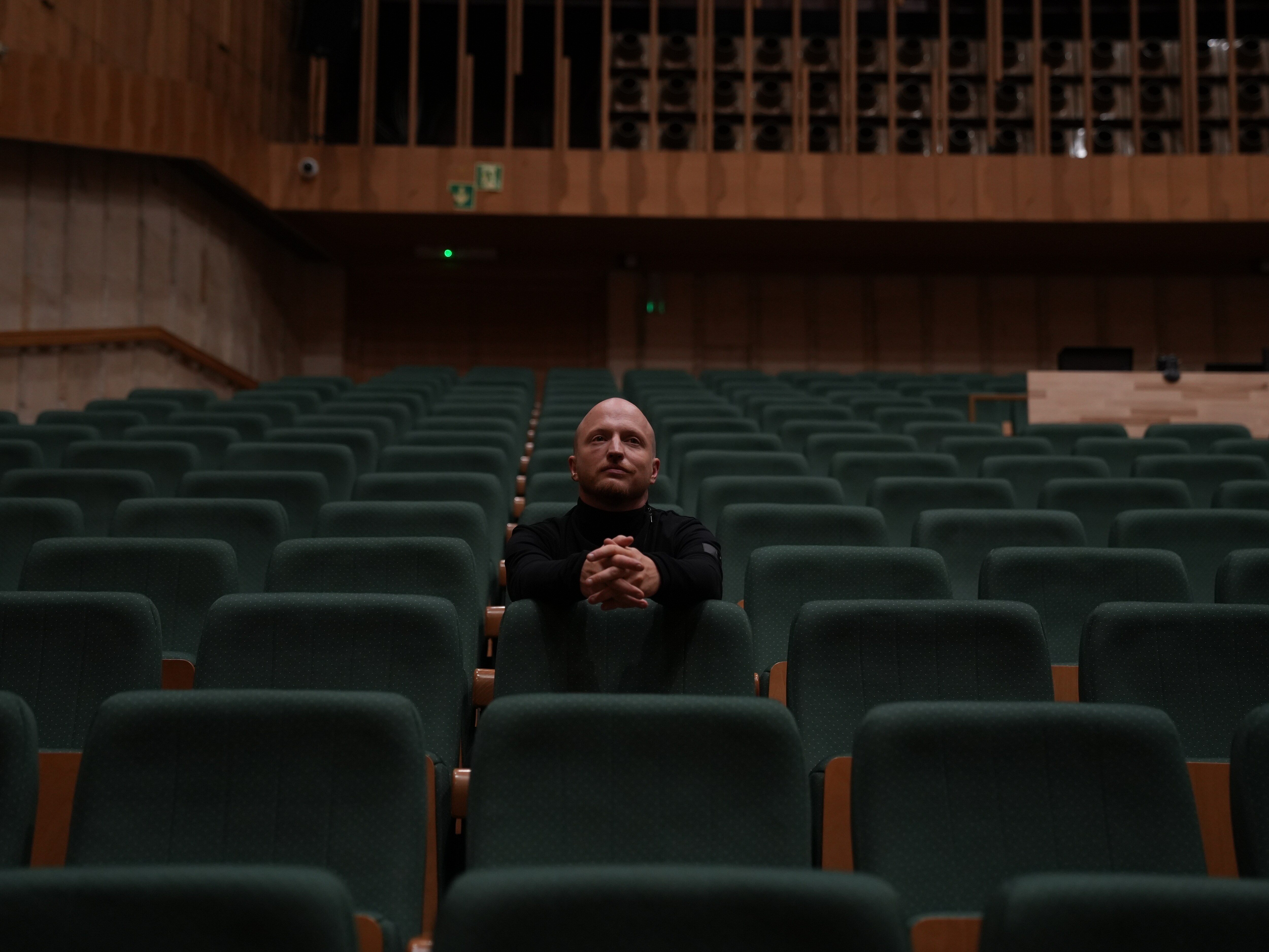 Wojciech Urbański siedzący samotnie w sali koncertowej.