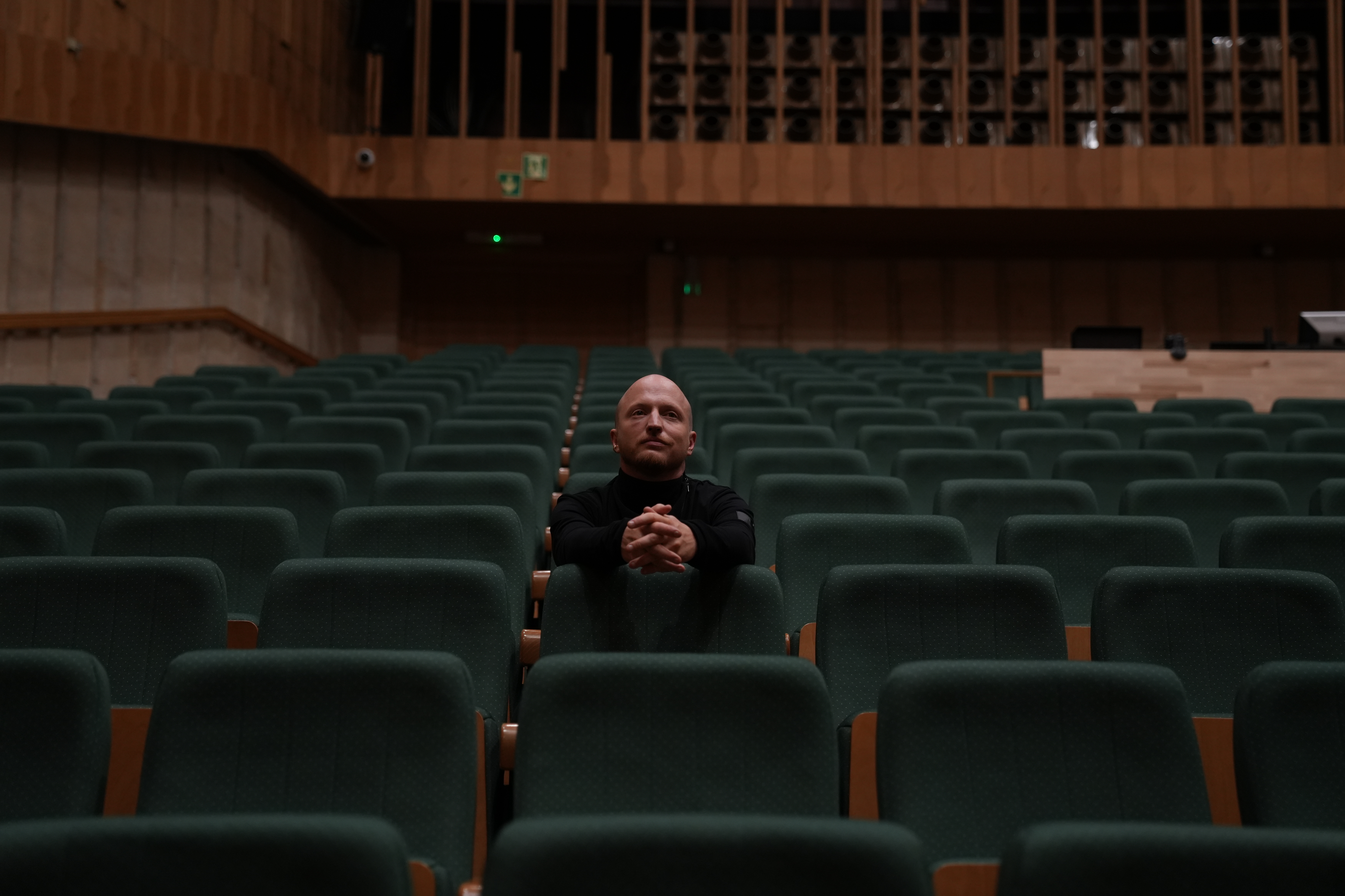 Wojciech Urbański | Mercedes-Benz Wojciech Urbański siedzący samotnie w sali koncertowej.