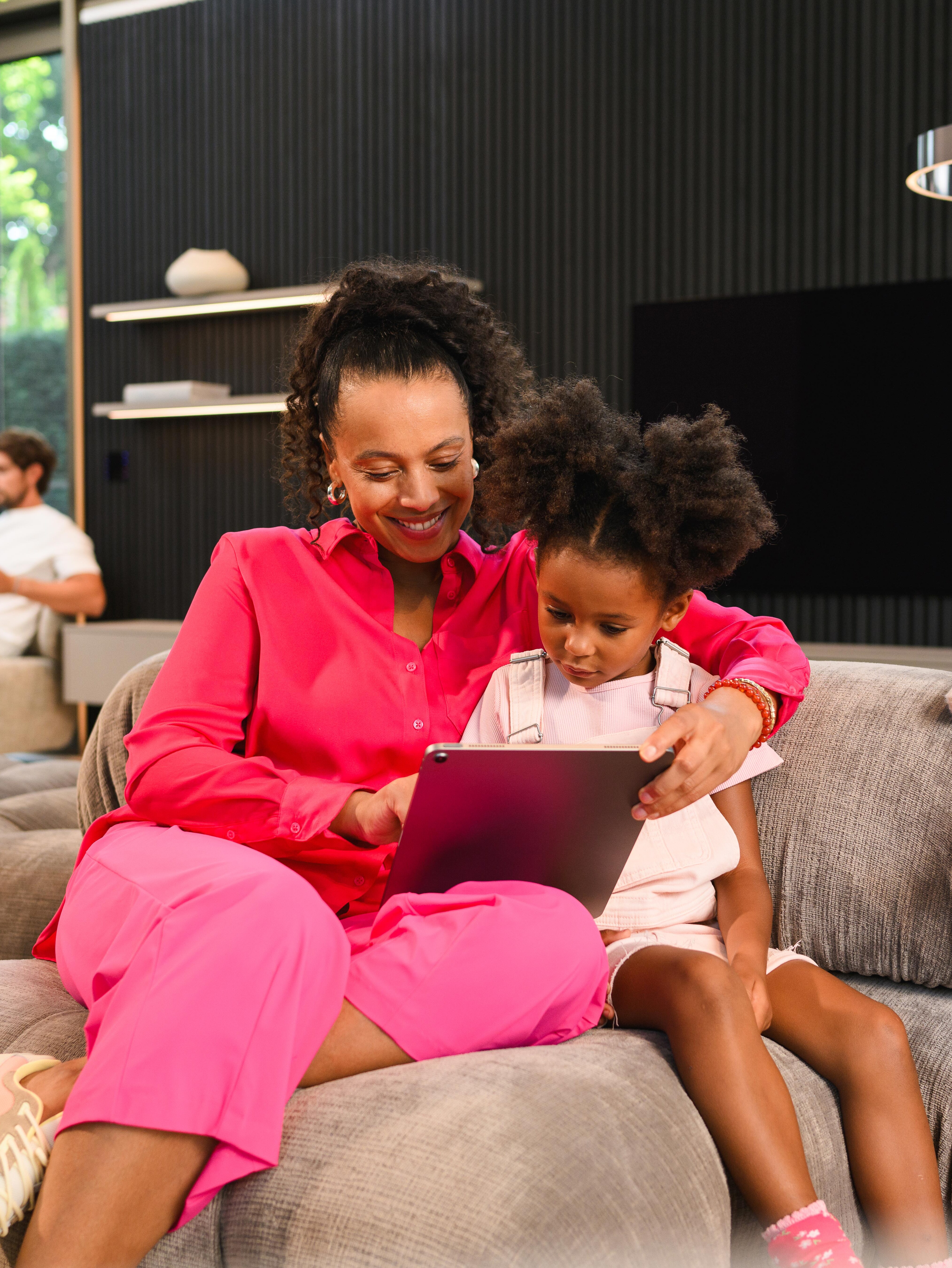 Kobieta z córką na kanapie przeglądają dokumenty na laptopie.