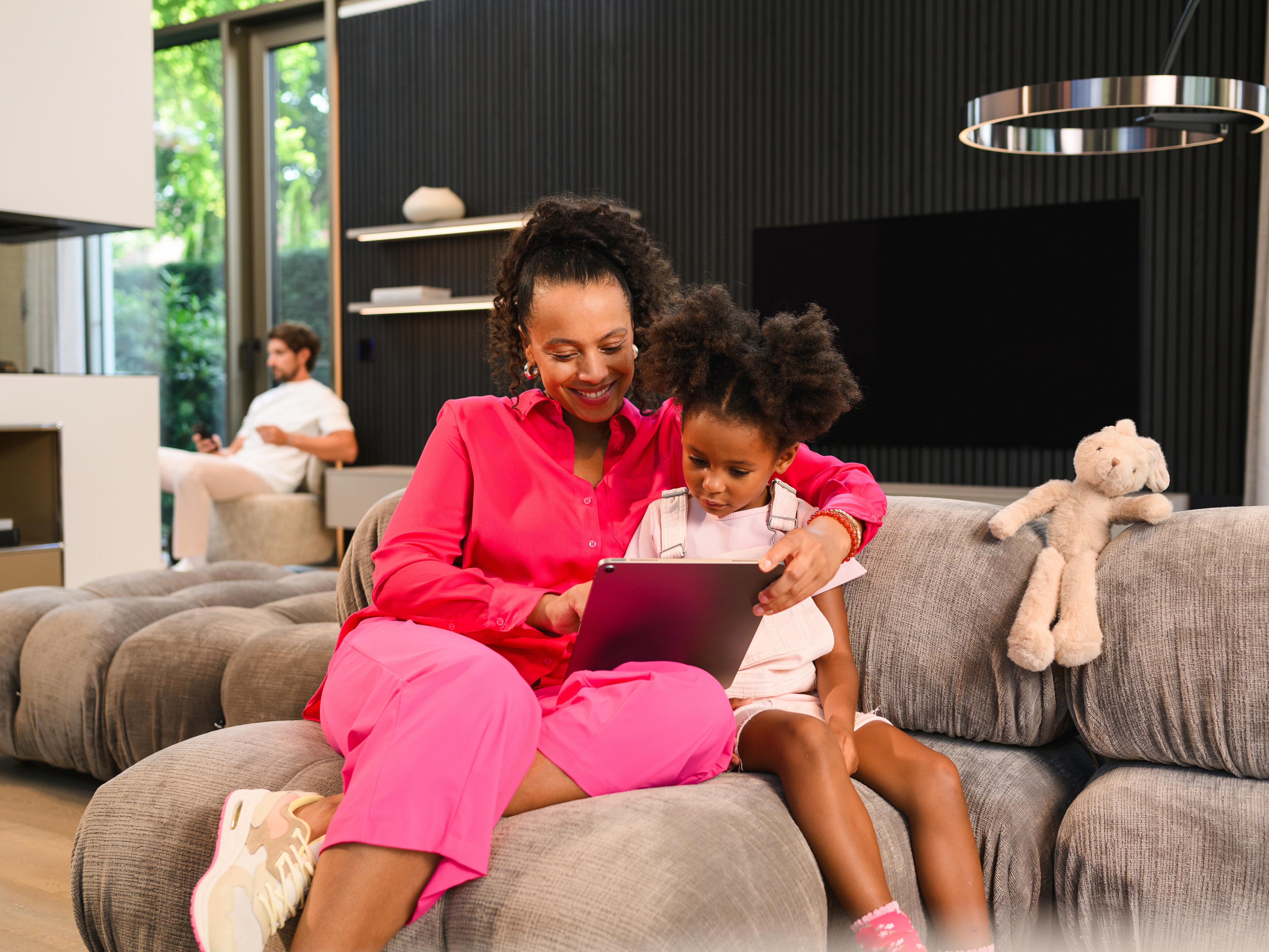 Kobieta z córką na kanapie przeglądają dokumenty na laptopie.