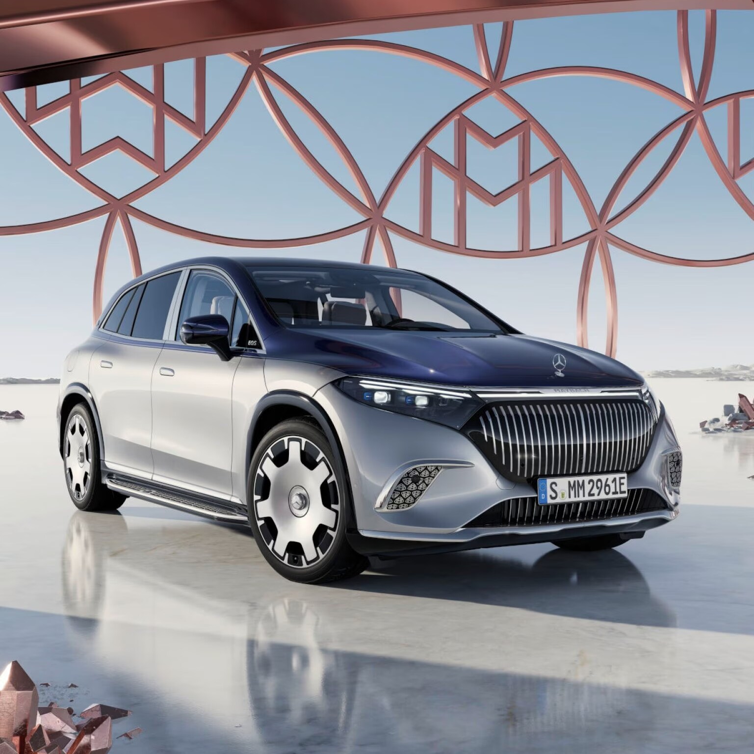 Srebrny Mercedes-Maybach EQS SUV na tle ażurowej konstrukcji z wzorem Mercedes-Maybach.