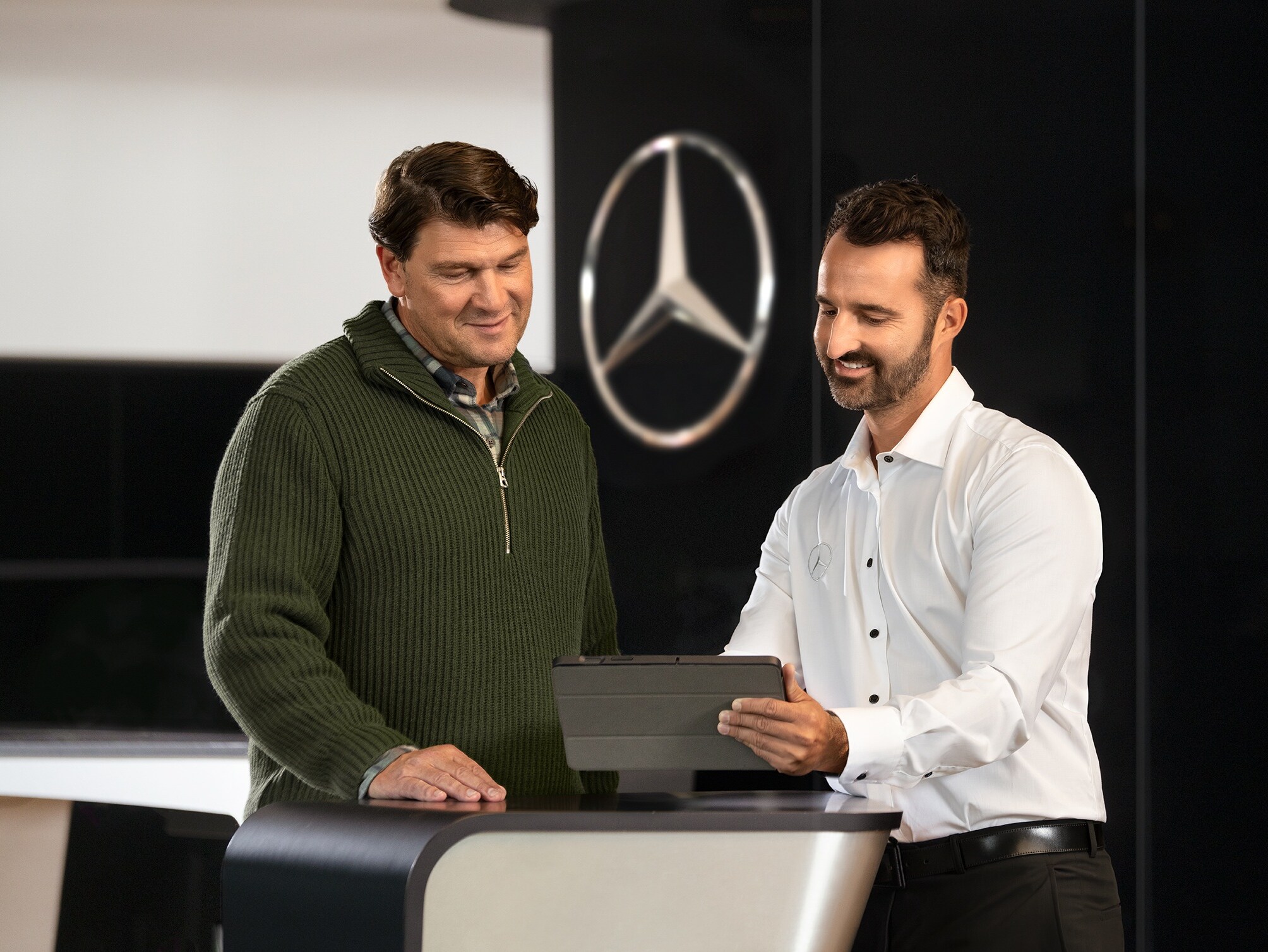 Dwóch mężczyzn rozmawia podczas przeglądania informacji na tablecie.