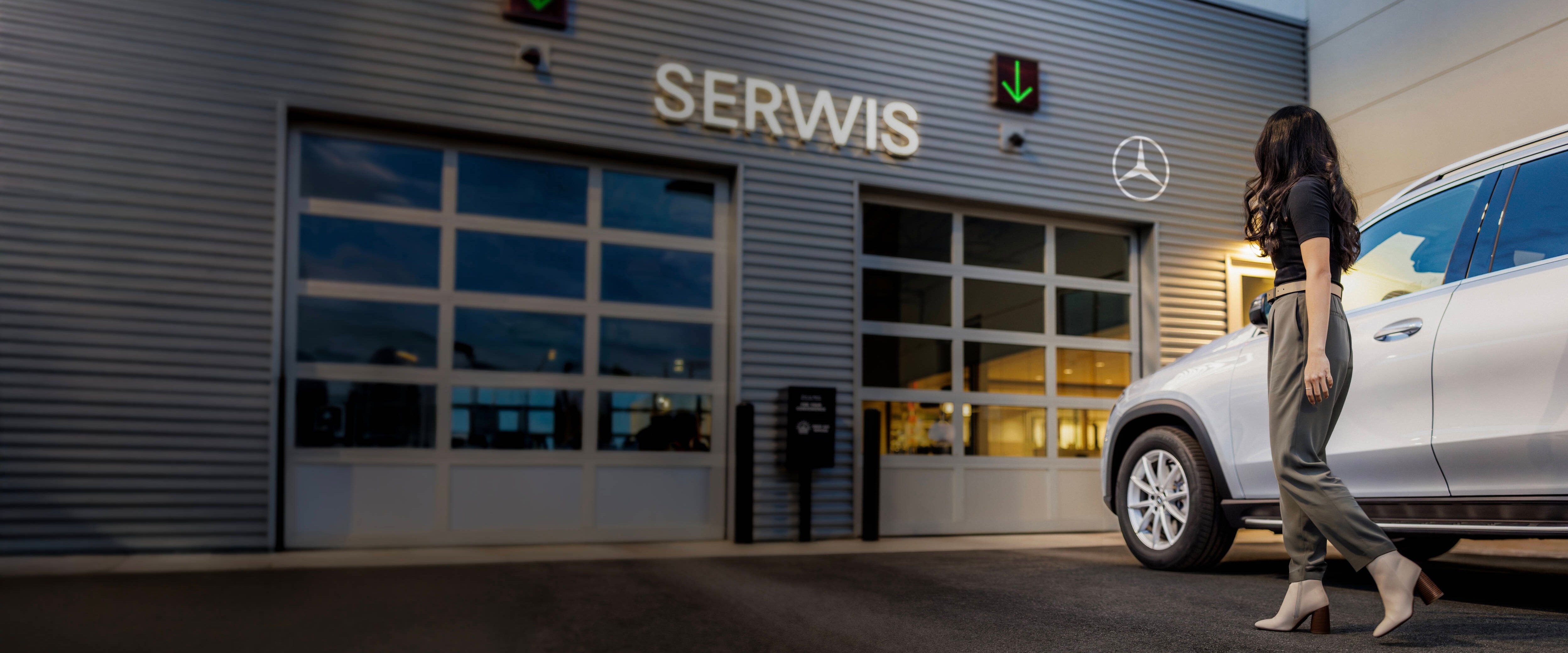 Kobieta wychodząca z samochodu zaparkowanego przed salonem serwisu Mercedes-Benz.