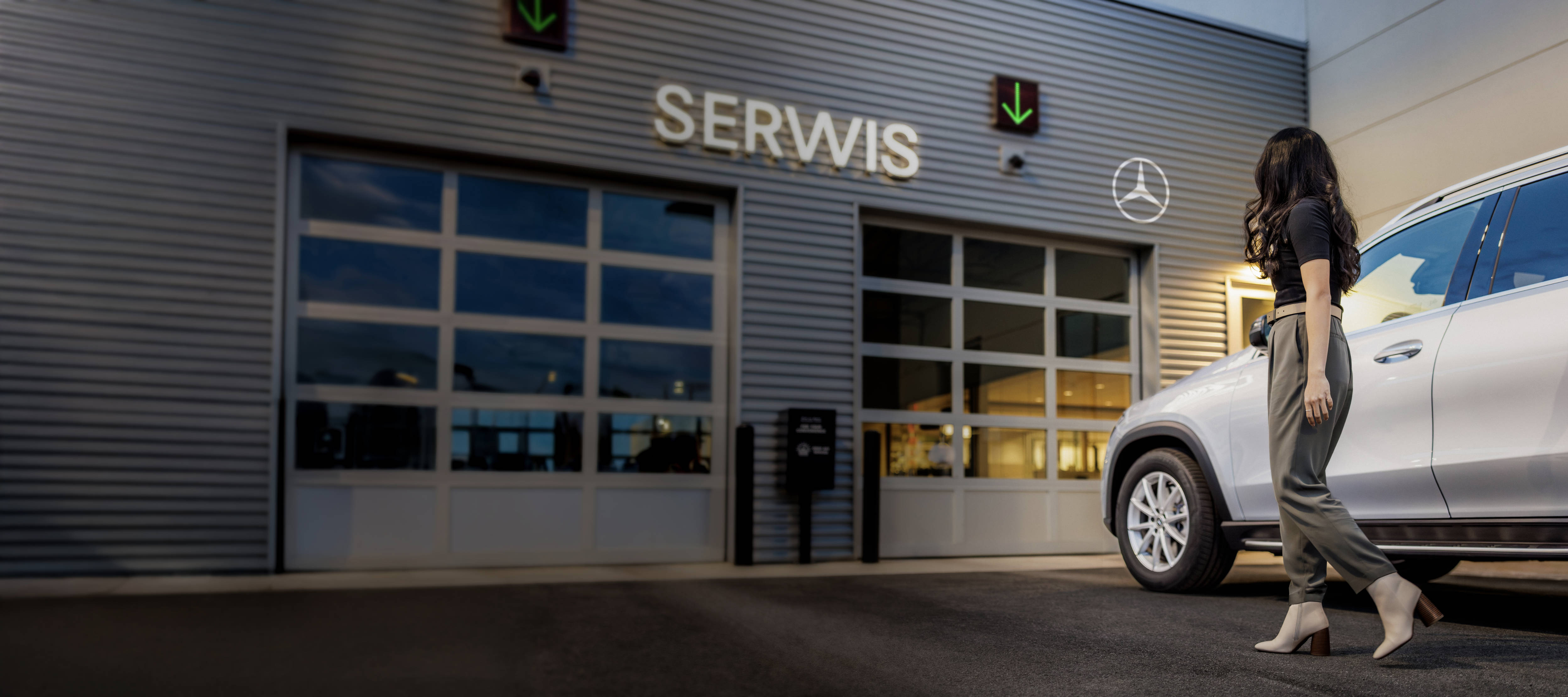 Twój Mercedes wraca do domu! Kobieta wychodząca z samochodu zaparkowanego przed salonem serwisu Mercedes-Benz.