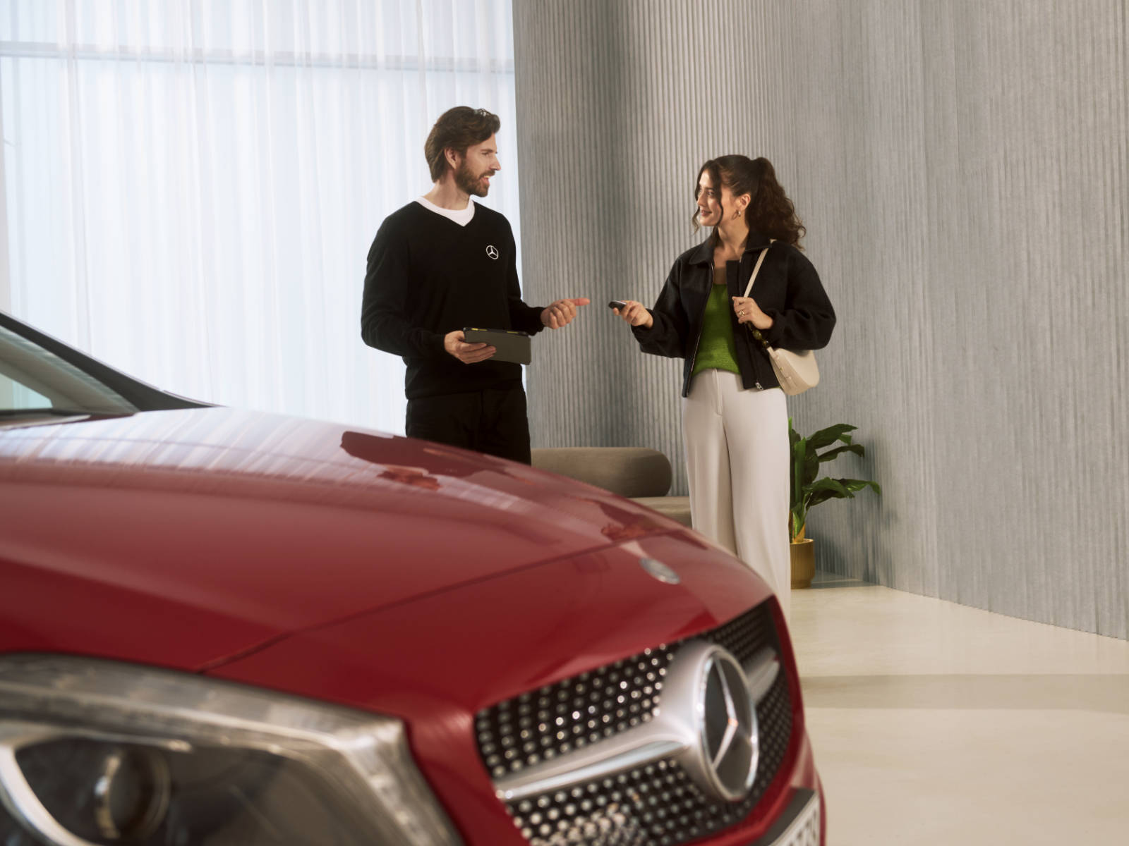 Serwisuj swój starszy model Mercedes-Benz. Kobieta i mężczyzna rozmawiają stojąc obok czerwonego Mercedes-Benz.