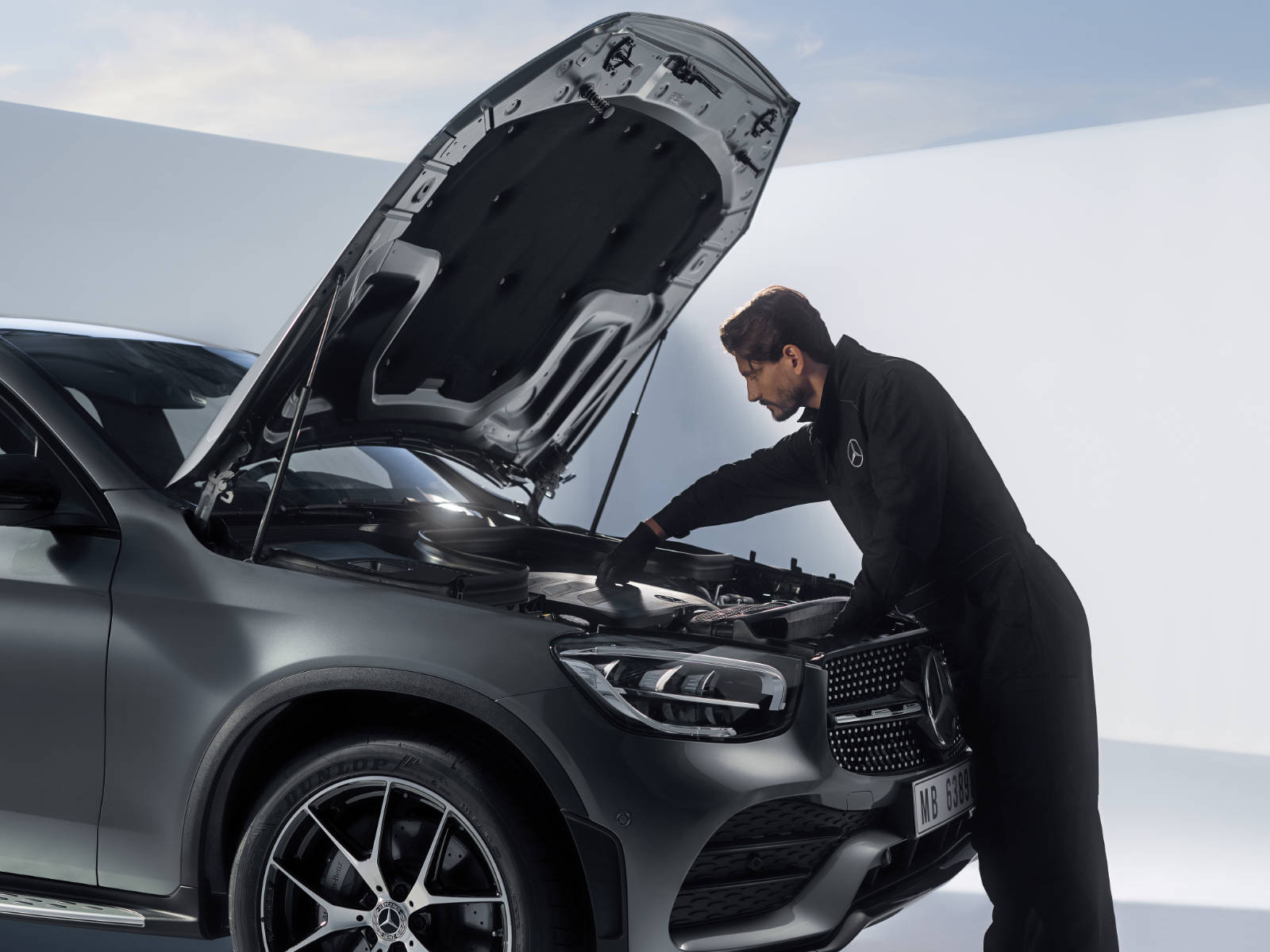 Serwisuj swój starszy model Mercedes-Benz. Pracownik serwisu Mercedes-Benz naprawia silnik.