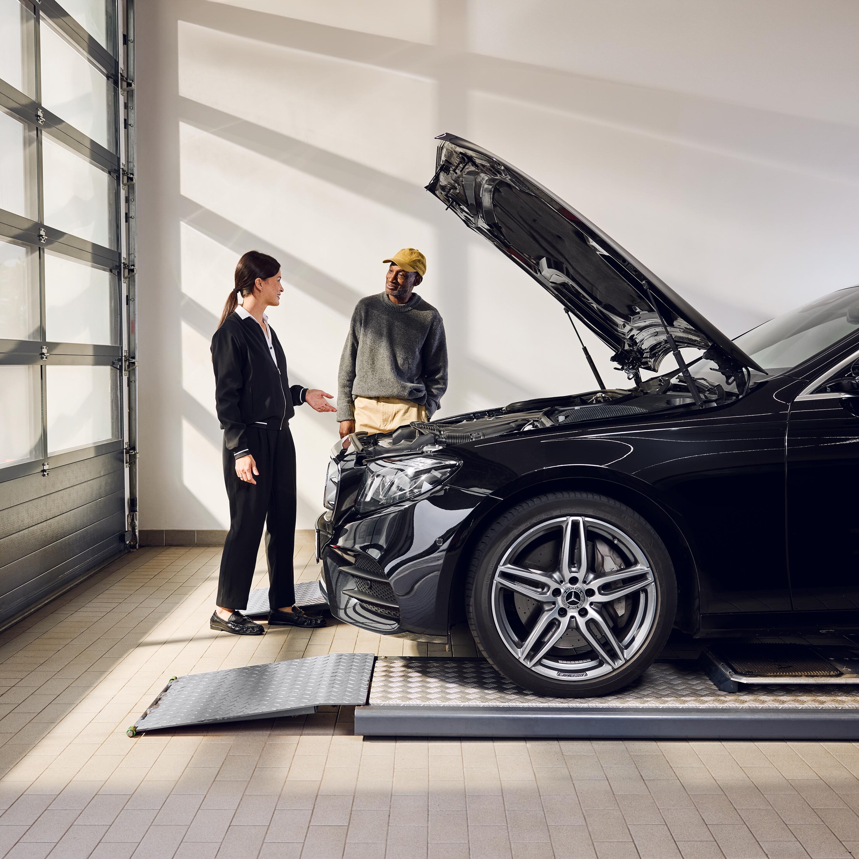 Samochód Mercedes-Benz stoi na rampie serwisowej z otwartą maską podczas wymiany oryginalnych części w centrum serwisowym.