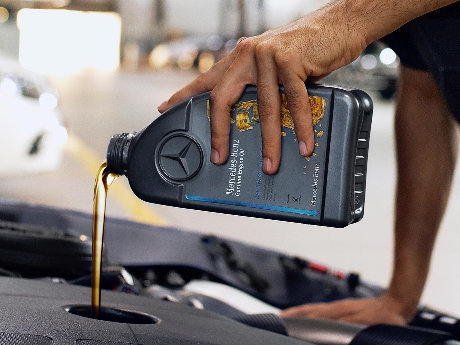 Zbliżenie na komorę silnika podczas wlewania oryginalnego oleju silnikowego Mercedes-Benz.