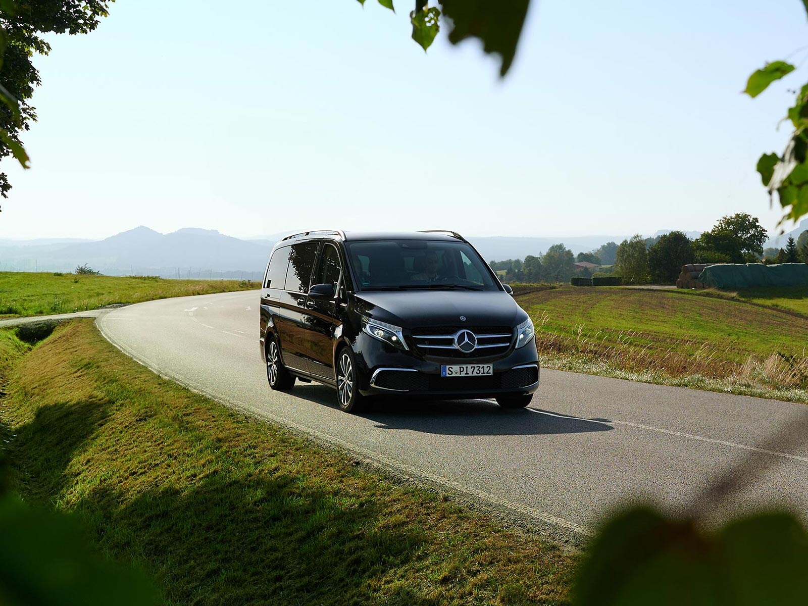 Czarna Klasa V Mercedes-Benz jadąca po wiejskiej drodze.