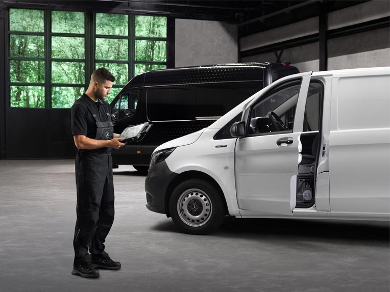 Pracownik serwisu Mercedes-Benz przeprowadza kontrolę białego Mercedesa Vito.